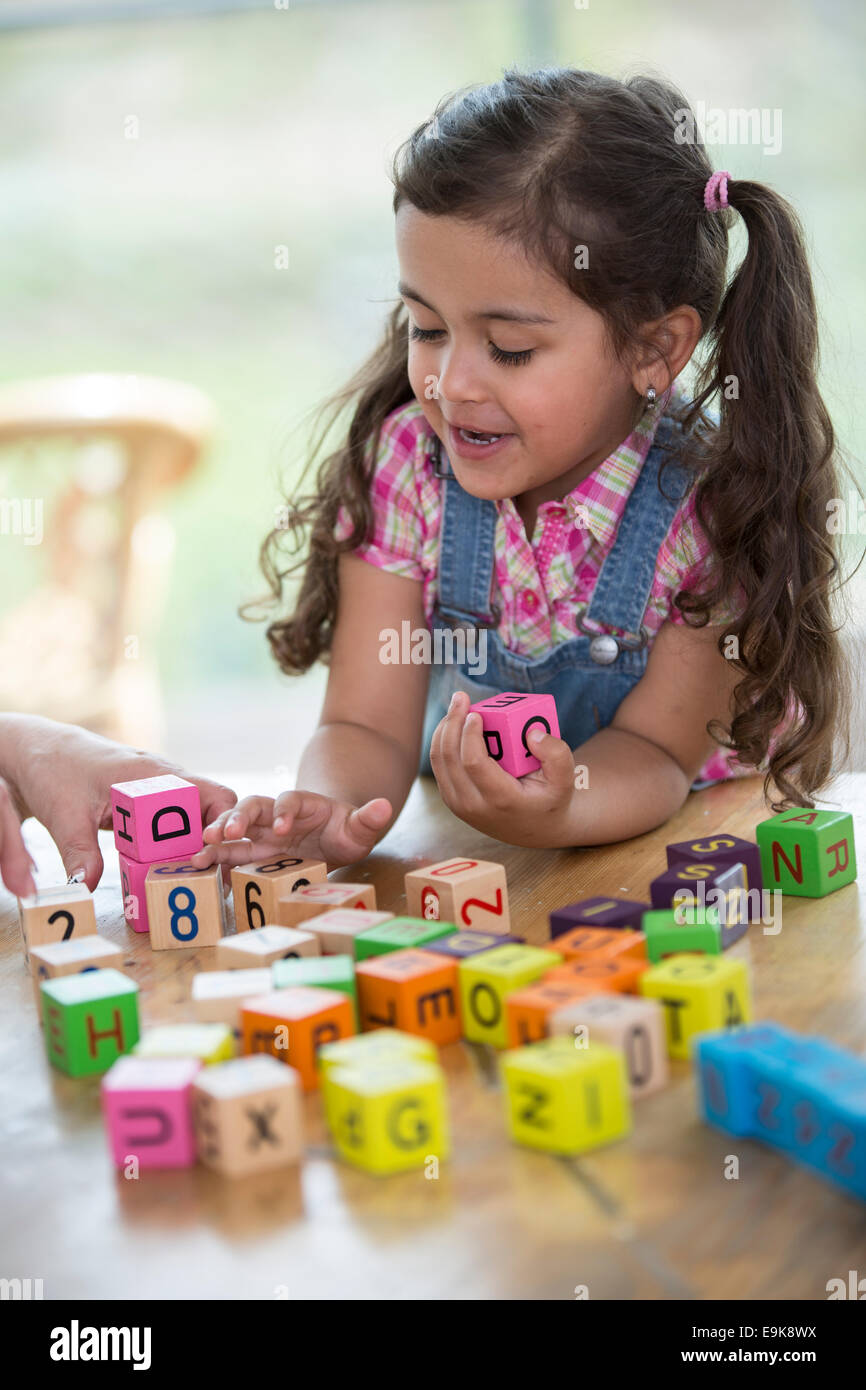 Glückliches Mädchen spielen mit Alphabet Blöcke am Tisch Stockfoto