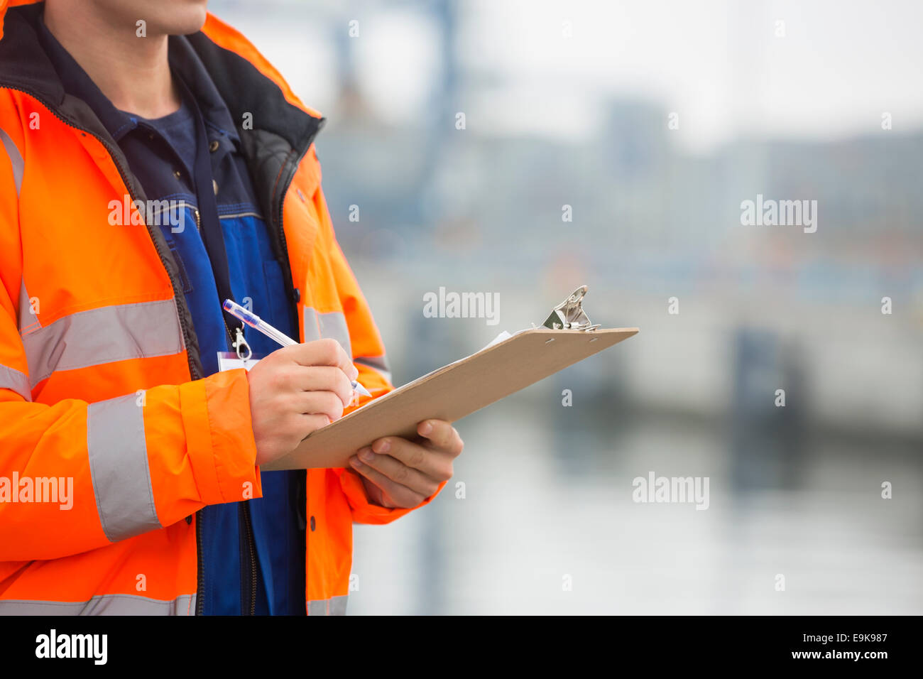 Mittelteil der Mitte erwachsenen Mannes in Zwischenablage im Frachthafen schreiben Stockfoto