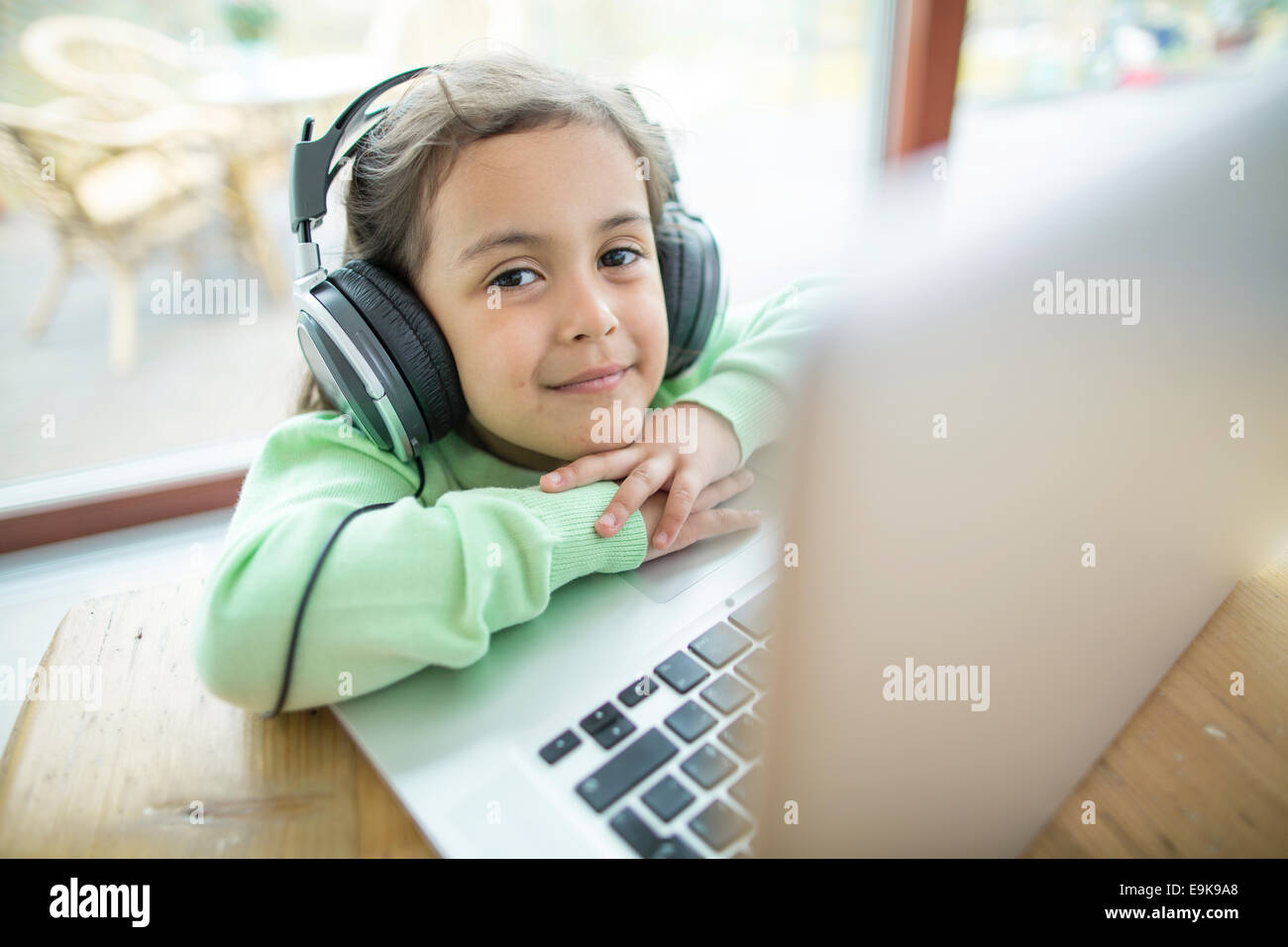 Porträt von netten Mädchen anhören von Musik über Kopfhörer mit Laptop am Tisch Stockfoto