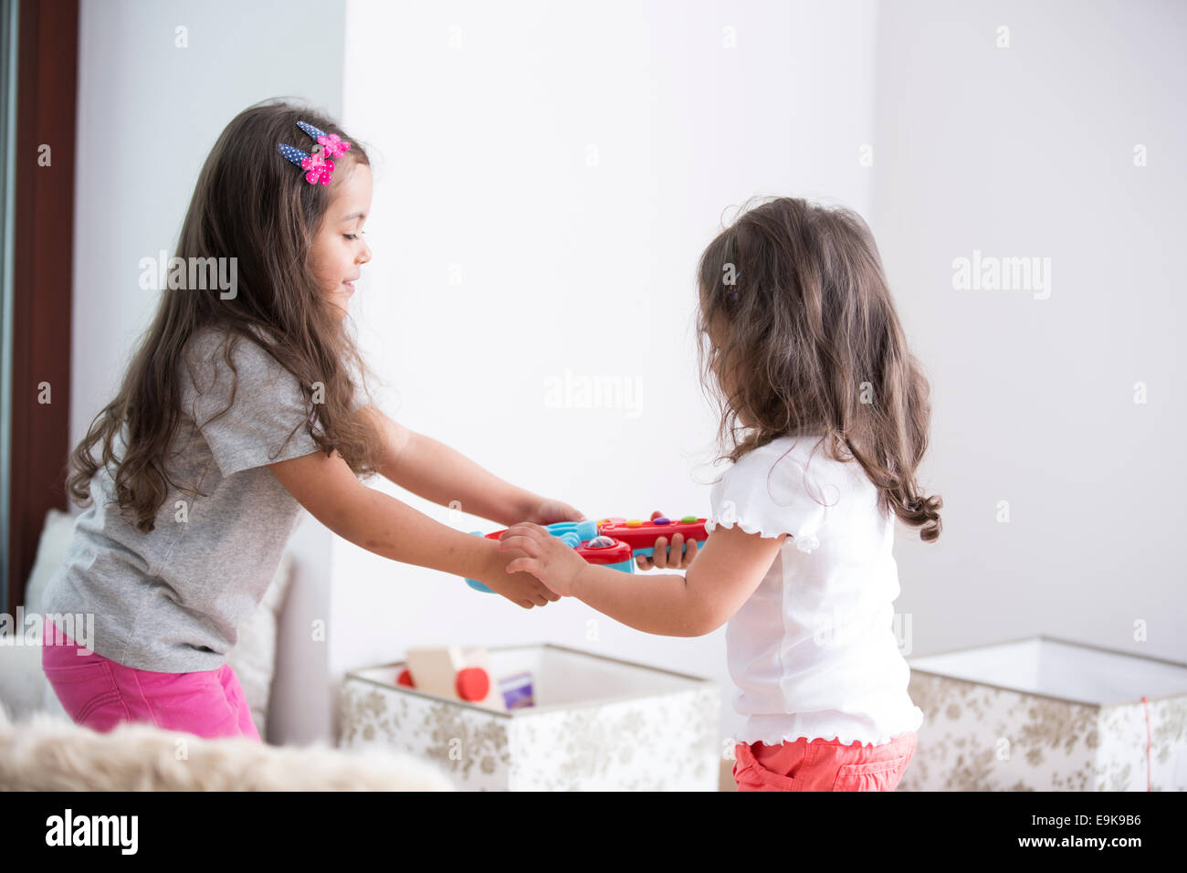 Seitenansicht der Schwestern kämpfen für Spielzeug-Gitarre zu Hause Stockfoto