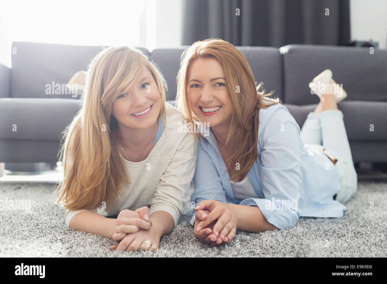 Porträt des Lächelns, Mutter und Tochter auf Teppich liegend Stockfoto
