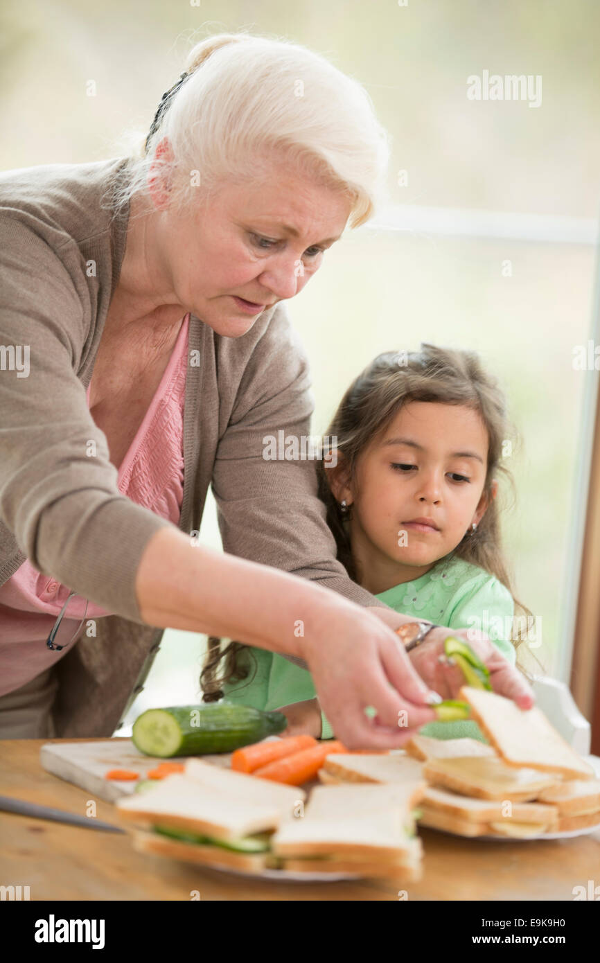 Mädchen auf der Suche bei Großmutter Sandwiches zu Hause vorbereiten Stockfoto