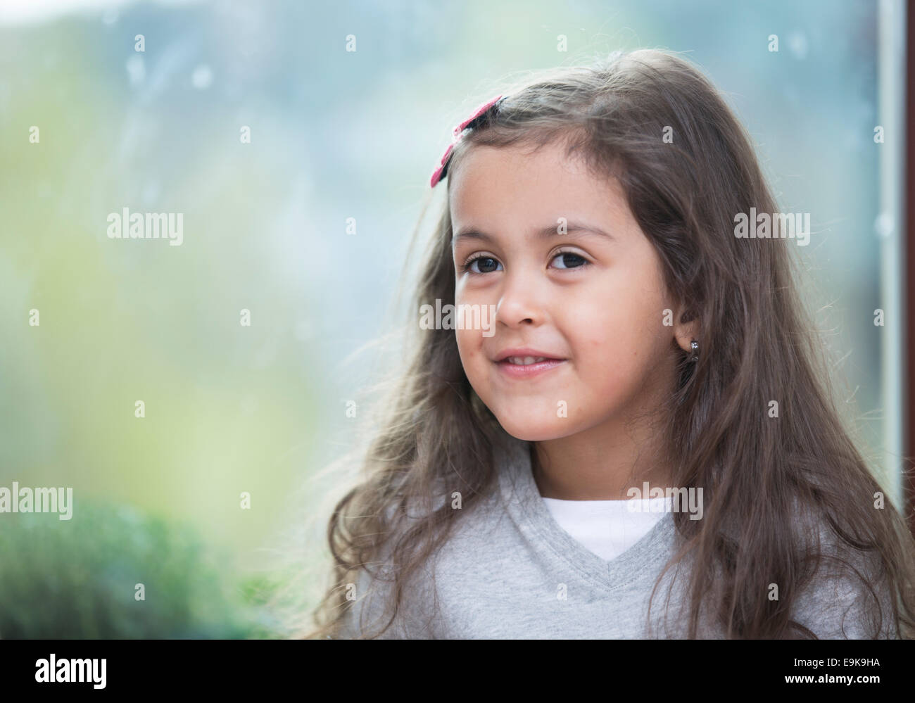 Porträt der niedliche kleine Mädchen gegen Glasfenster zu Hause Stockfoto