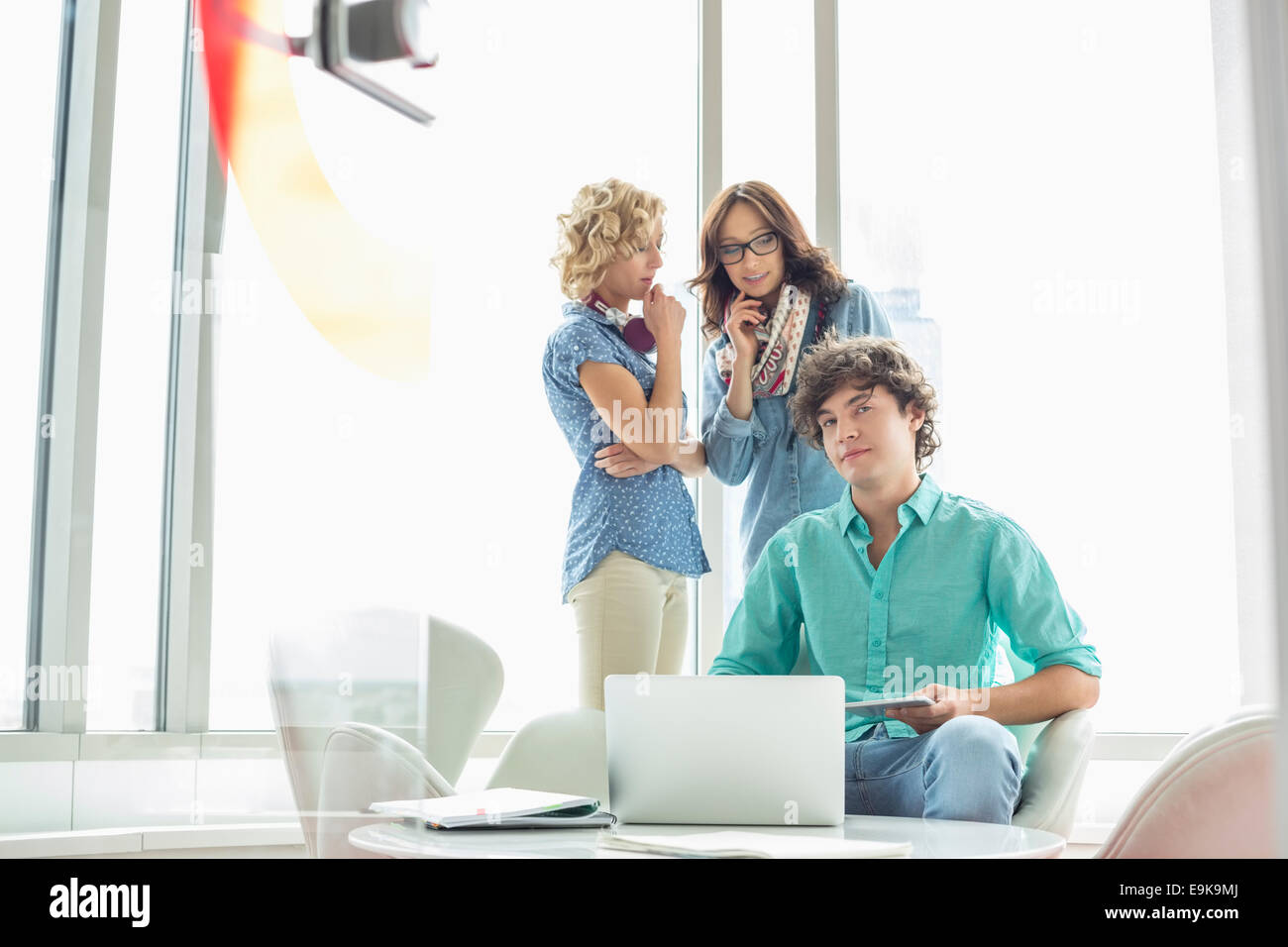 Porträt von zuversichtlich Geschäftsmann mit weiblichen Kollegen im Hintergrund im Gespräch am Tisch sitzen Stockfoto