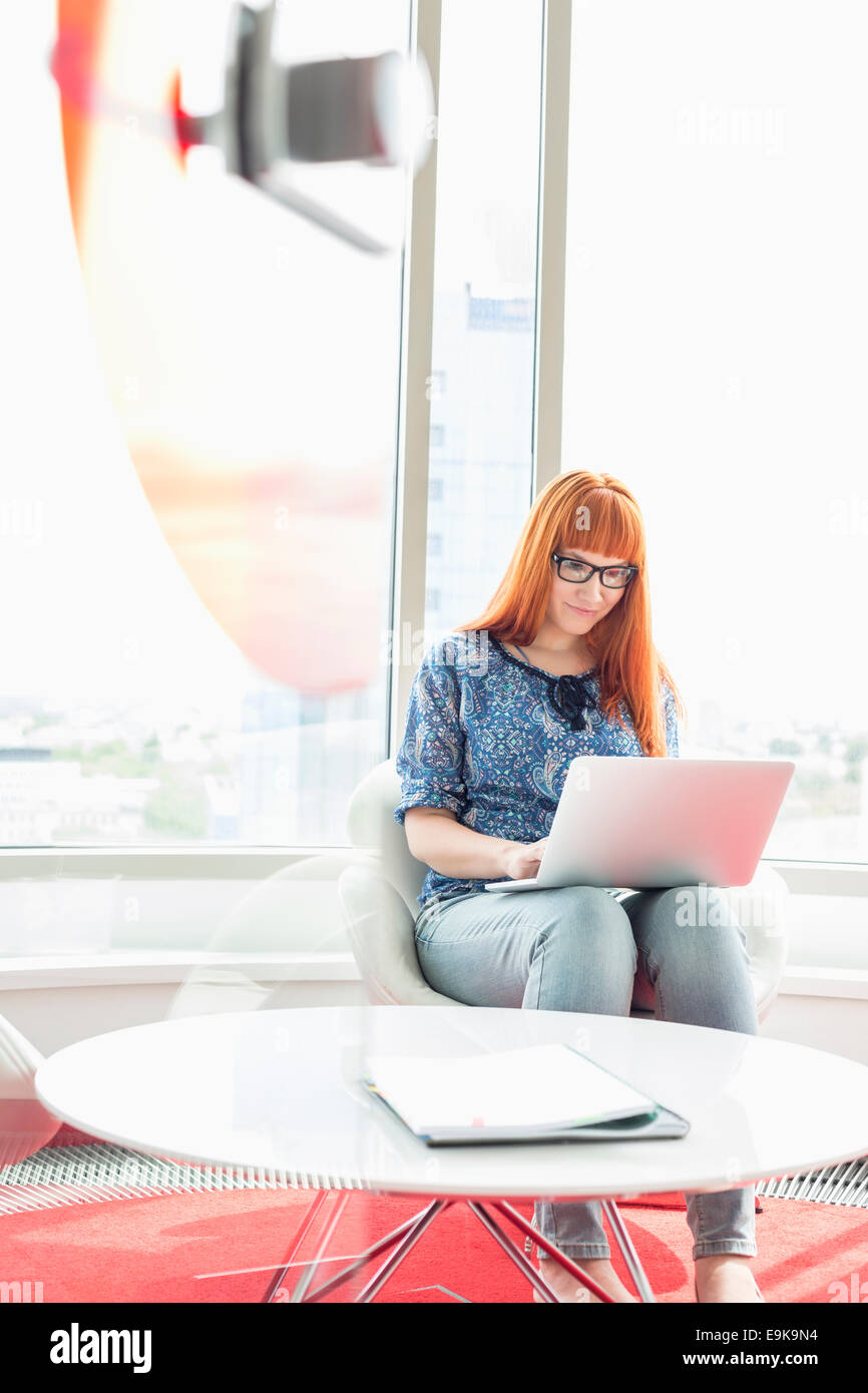 Junge Geschäftsfrau mit Laptop in Kreativbüro Stockfoto