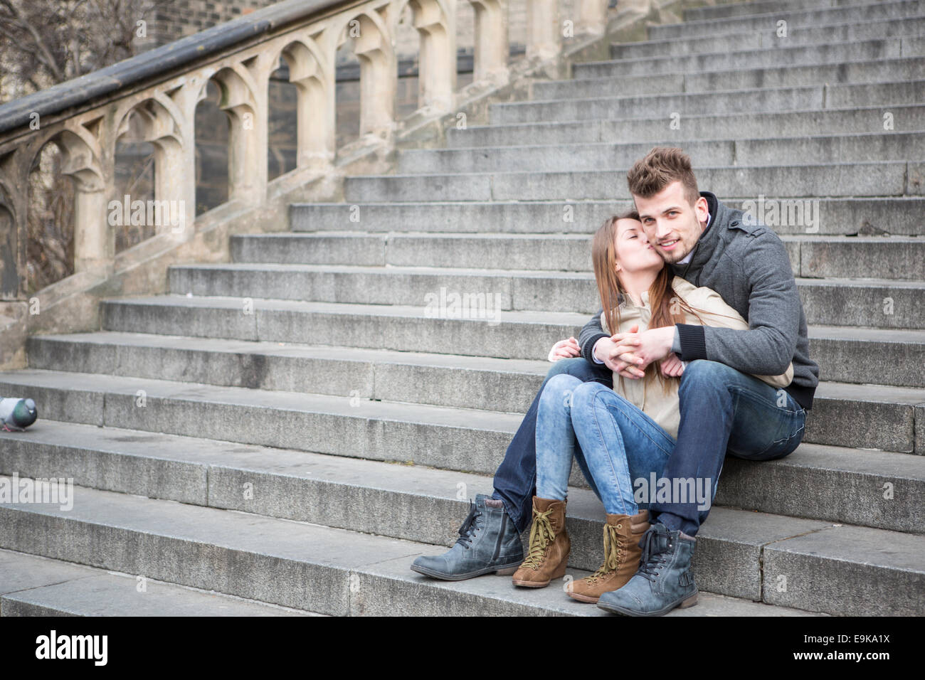 Voller Länge liebenden Frau küssen Mann sitzend auf Schritte im freien Stockfoto