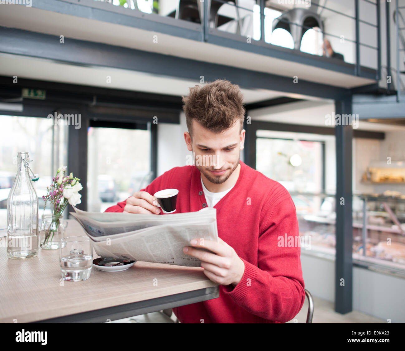 Junger Mann beim Kaffeetrinken im Café lesen Zeitung Stockfoto