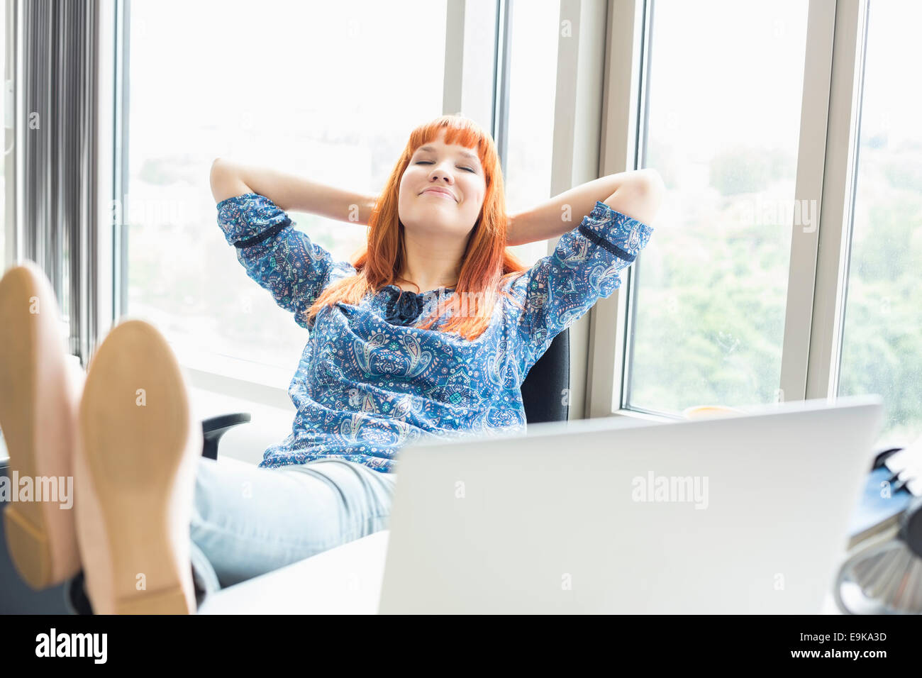 Geschäftsfrau mit Füße am Schreibtisch im Kreativbüro entspannen Stockfoto