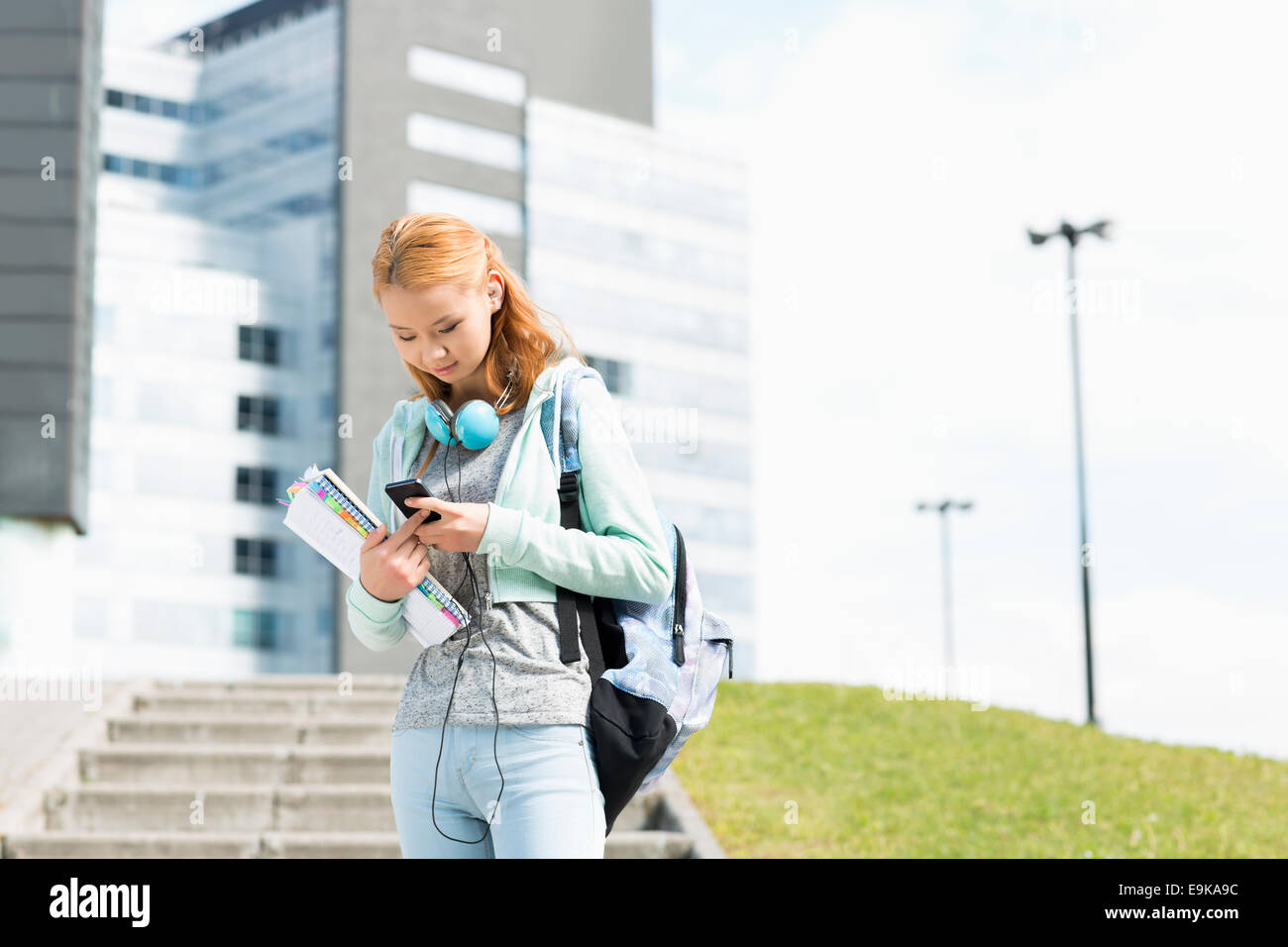Junge Frau mit Smartphone am College campus Stockfoto