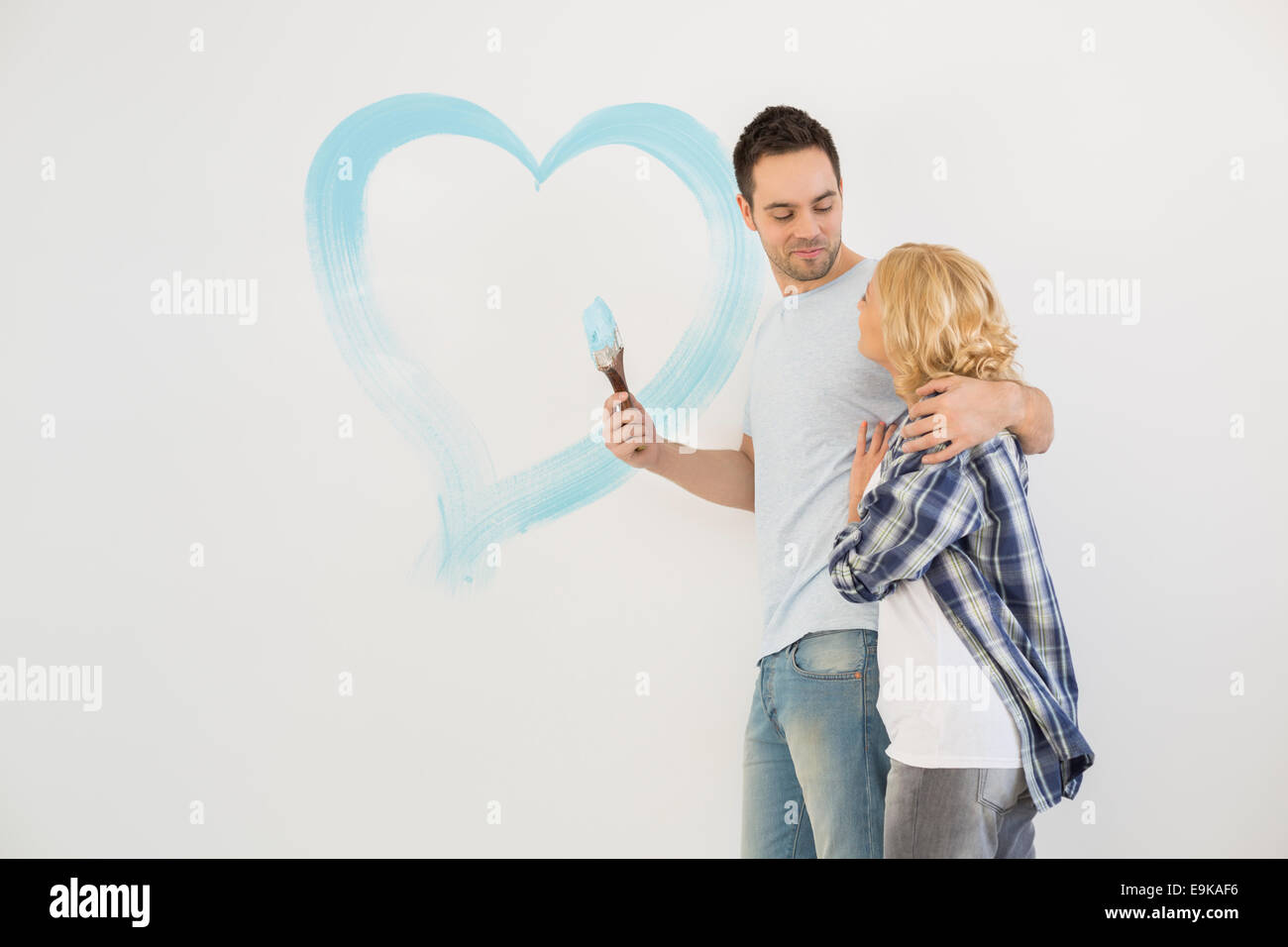 Liebespaar im mittleren Erwachsenenalter mit gemalten Herzen an Wand Stockfoto