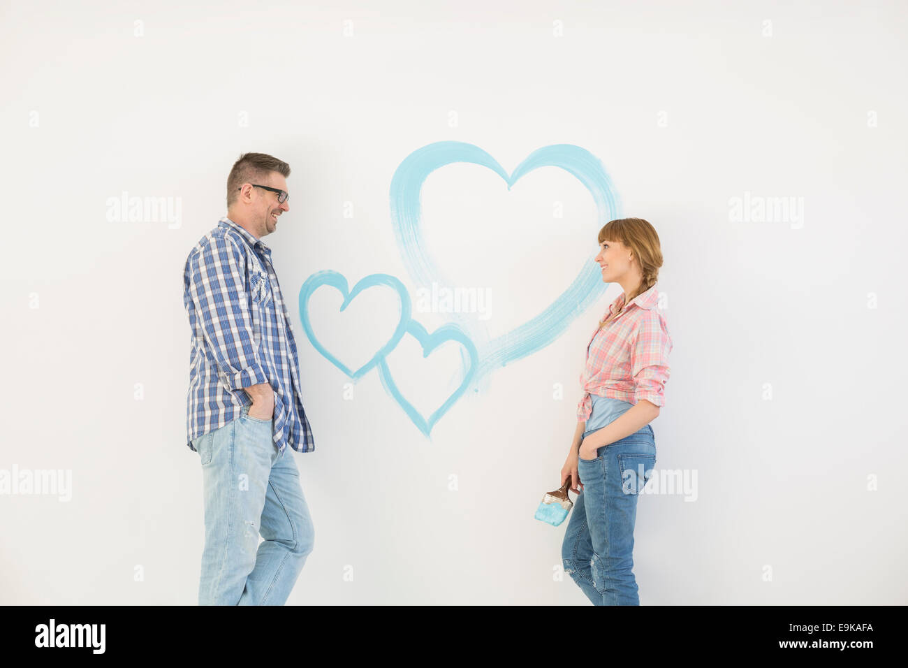 Mid-Adult paar sahen einander mit gemalten Herzen an Wand Stockfoto