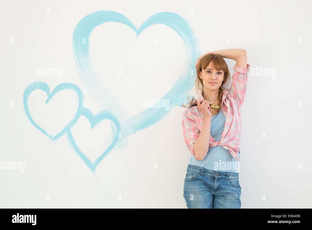 Portrait der schönen Frau mit Pinsel mit Herzen an die Wand gemalt Stockfoto