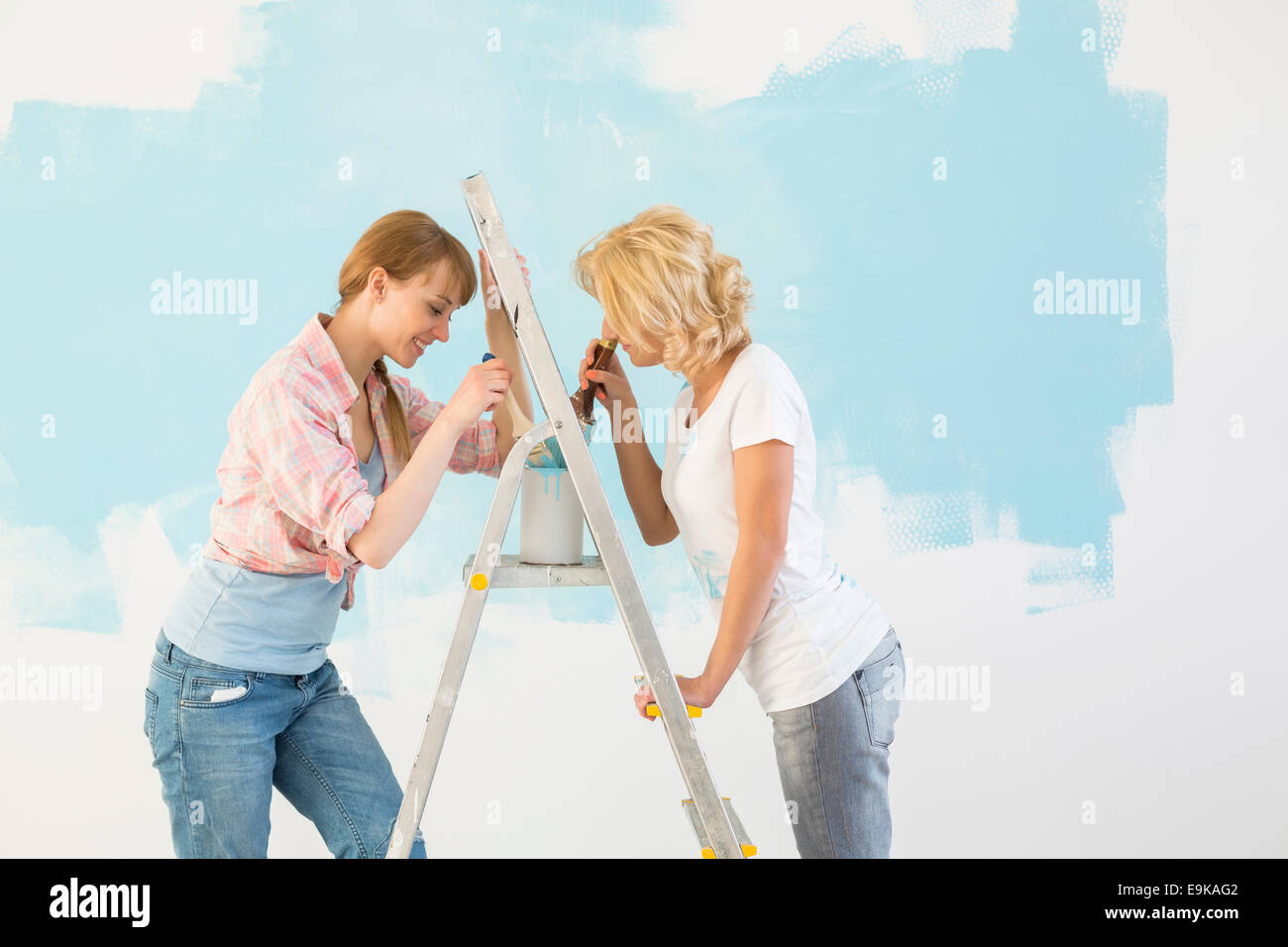 Seitenansicht der Freundinnen malen gemeinsam im neuen Zuhause Stockfoto