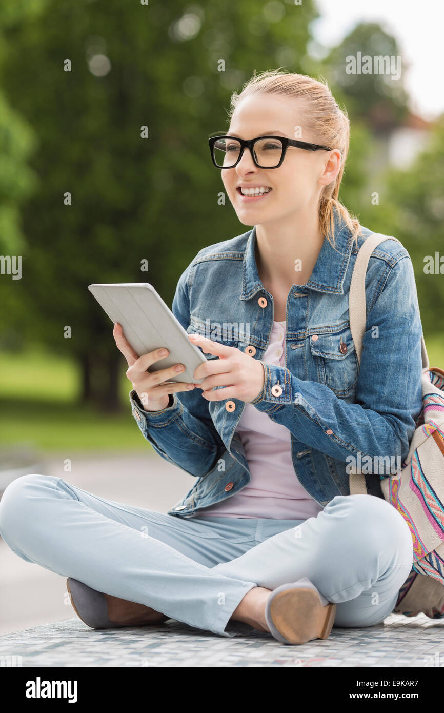 Voller Länge lächelnder junge weibliche Studentin mit Tablet PC im park Stockfoto