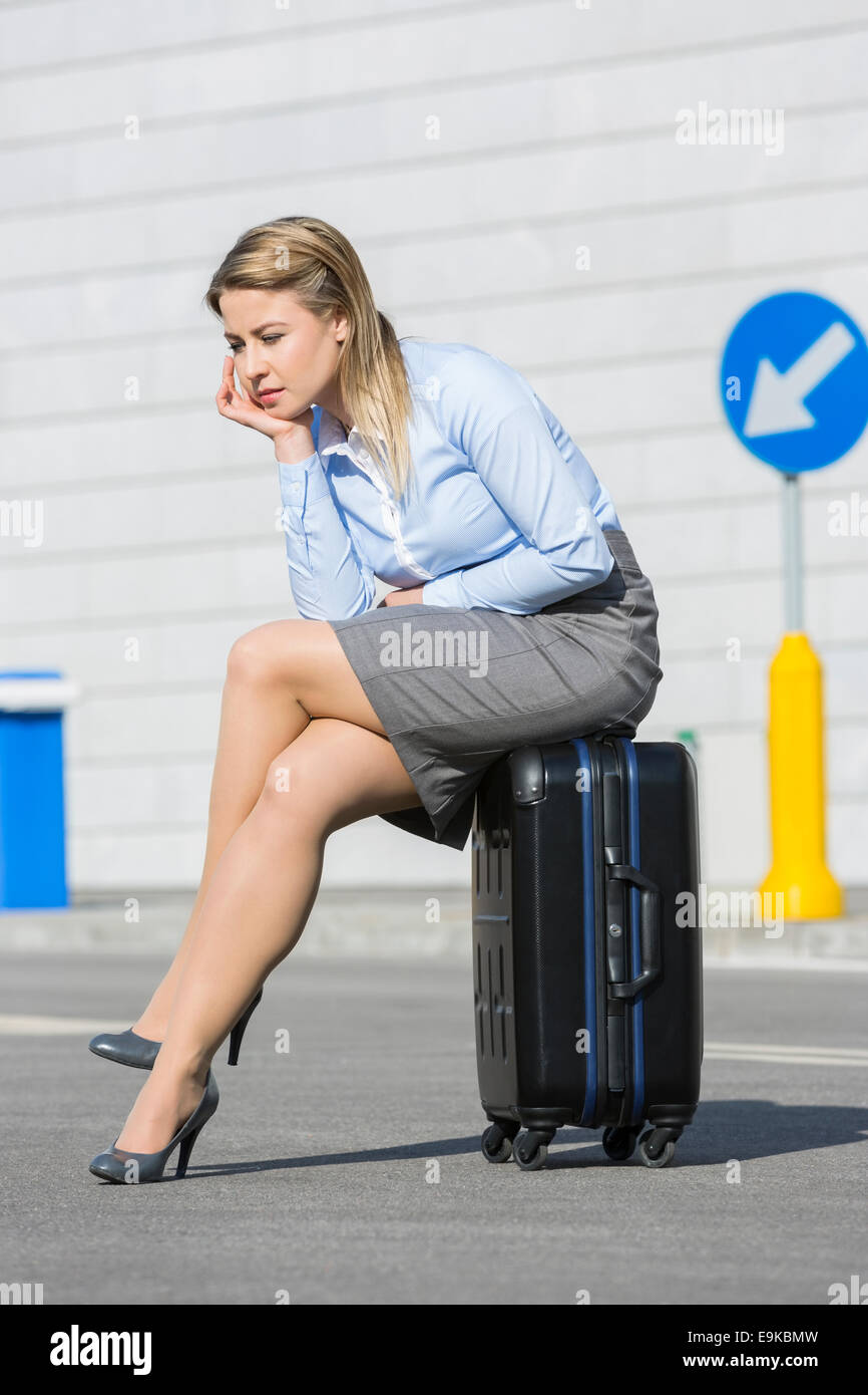 Gesamte Länge der erschöpfte Geschäftsfrau sitzen auf Gepäck Stockfoto