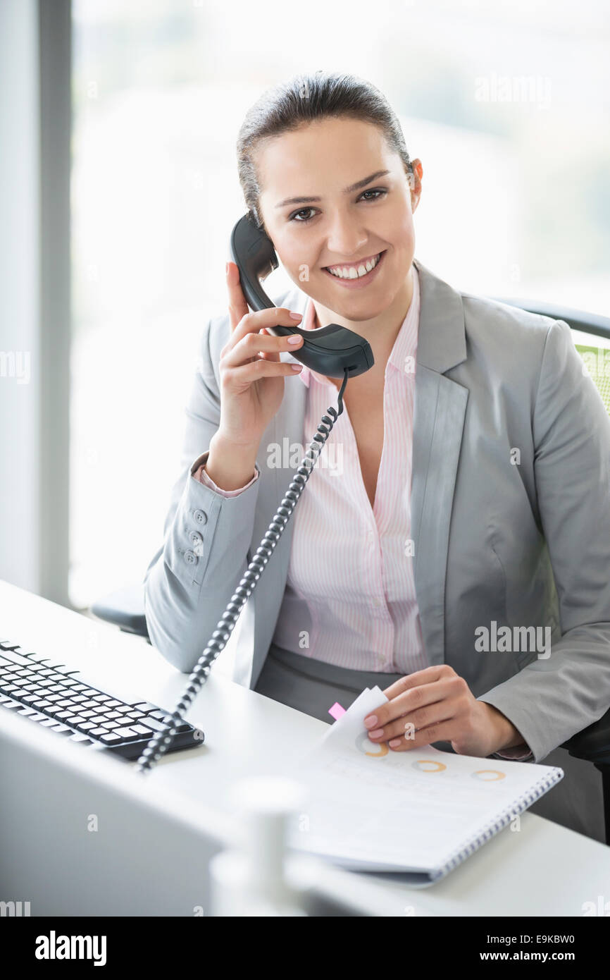 Lächelnde junge Geschäftsfrau Gespräch am Telefon im Büro Stockfoto