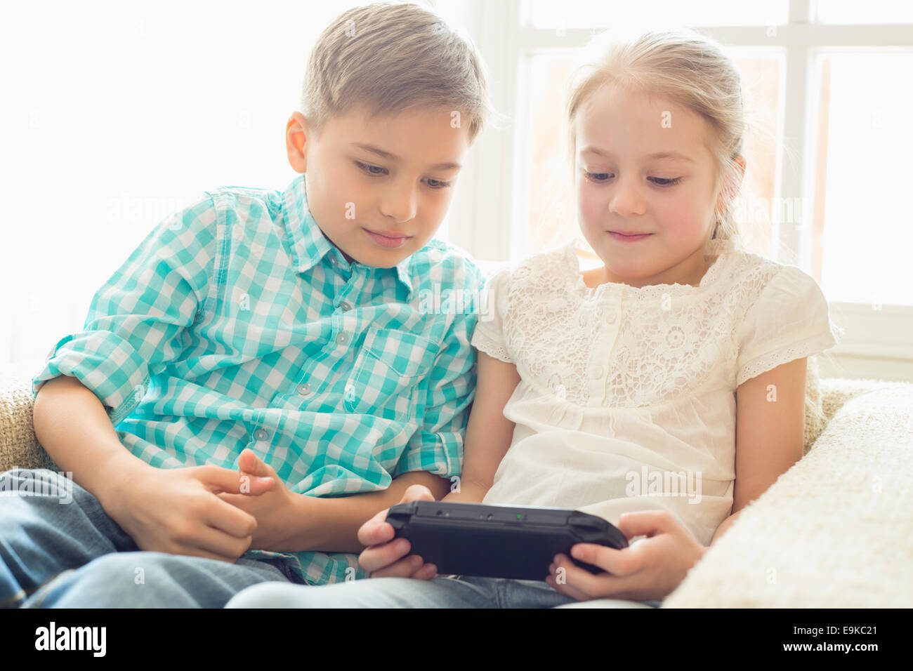 Geschwister, die tragbare Videospiel zu Hause spielen Stockfoto
