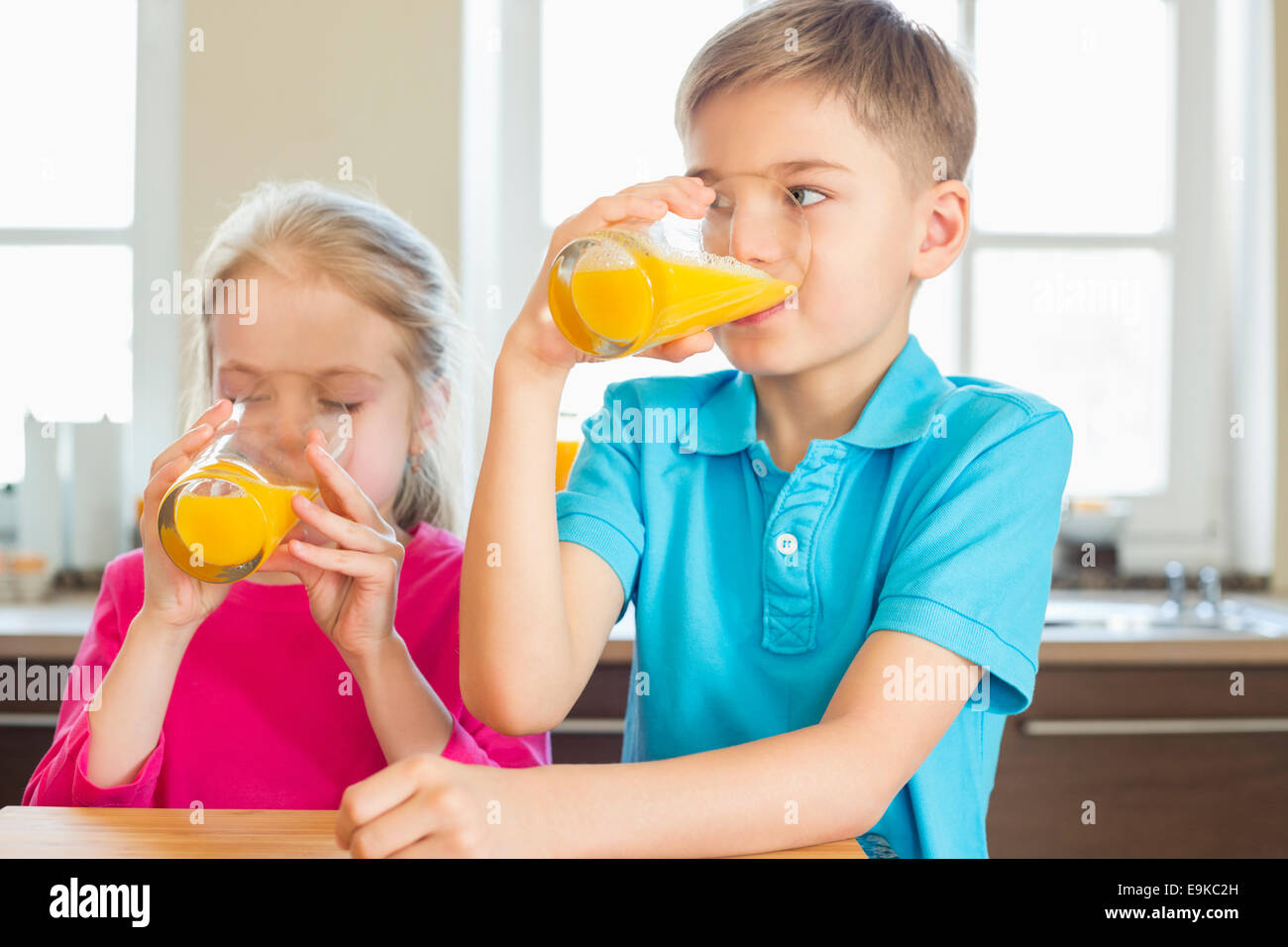 Geschwister trinken Orangensaft in der Küche zu Hause Stockfoto