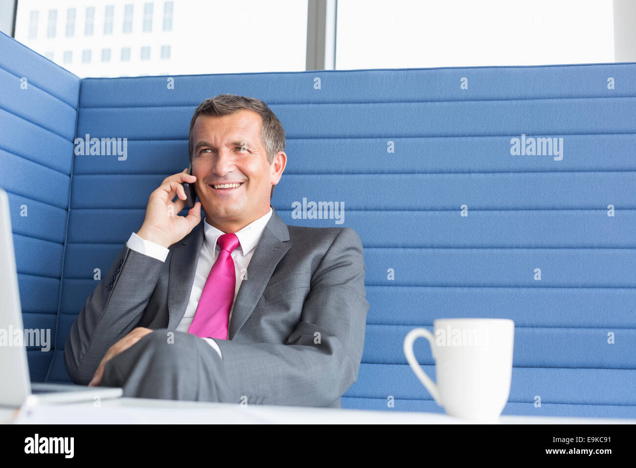 Lächelnde reifer Geschäftsmann reden über Handy im Büro Stockfoto