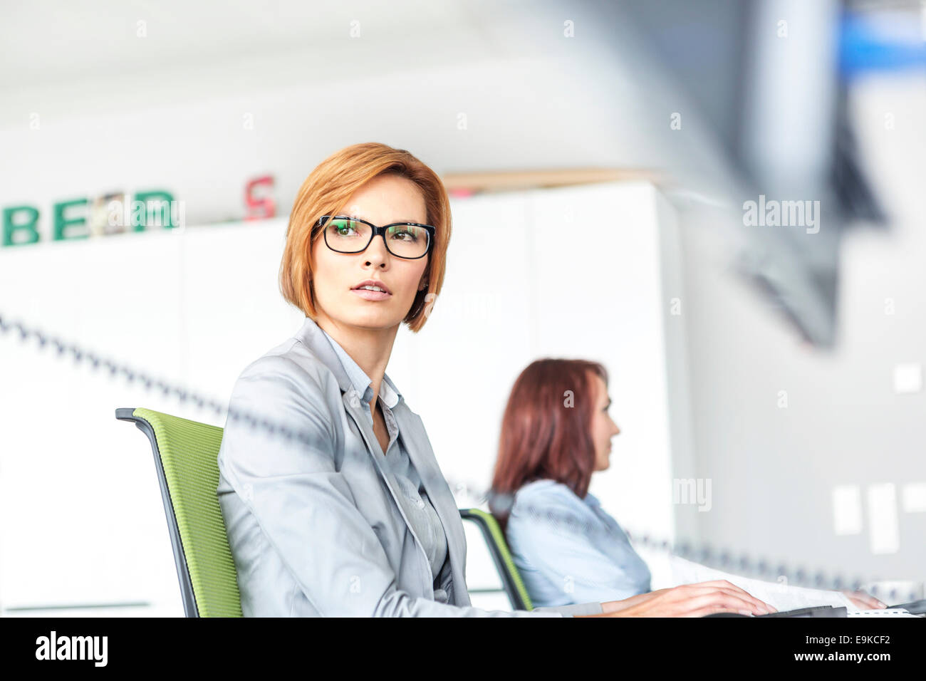 Junge Geschäftsfrau mit Kollegen im Hintergrund im Büro am Computer arbeiten Stockfoto