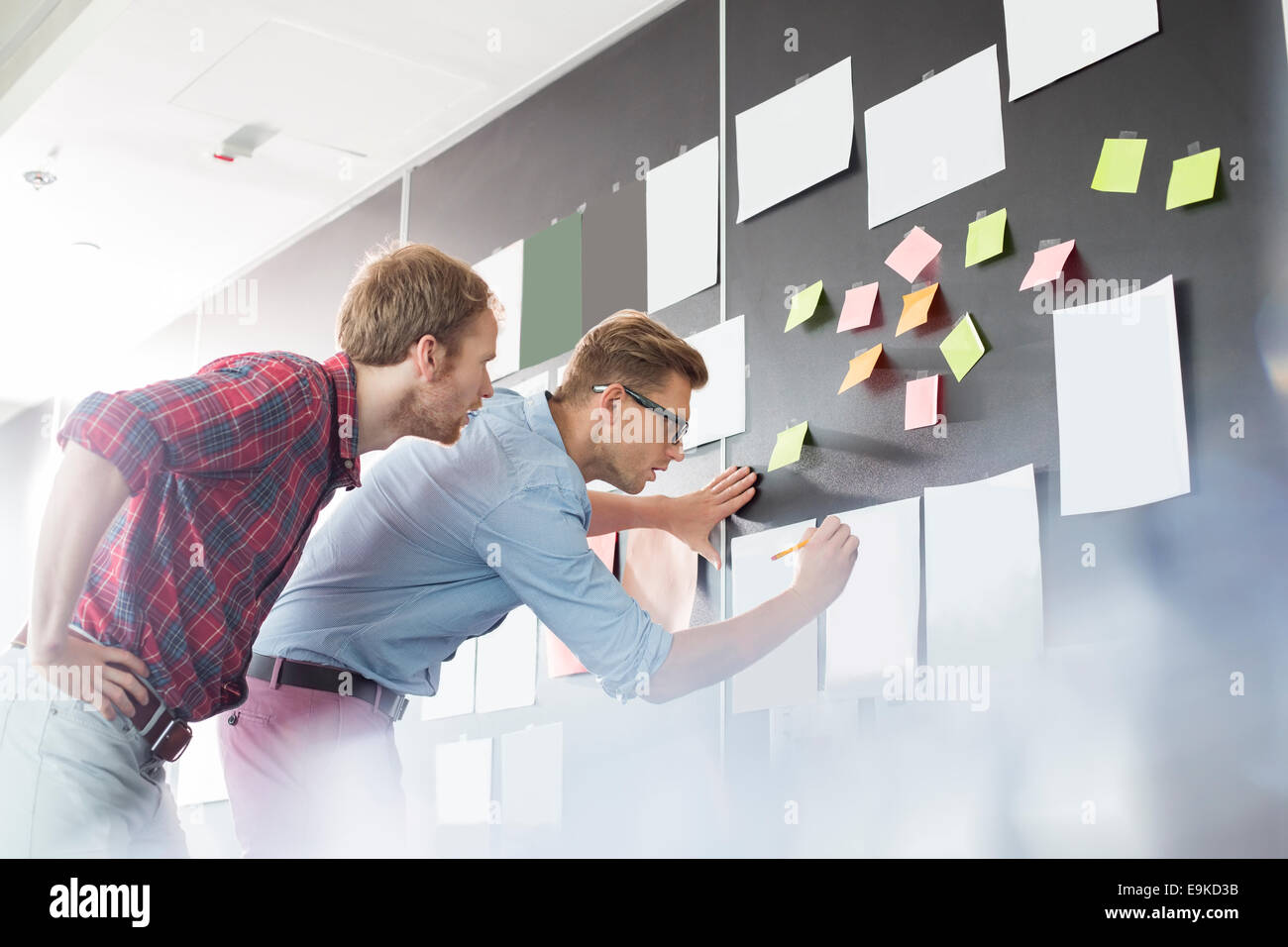 Geschäftsleute, die Analyse von Dokumenten an Wand im Büro Stockfoto