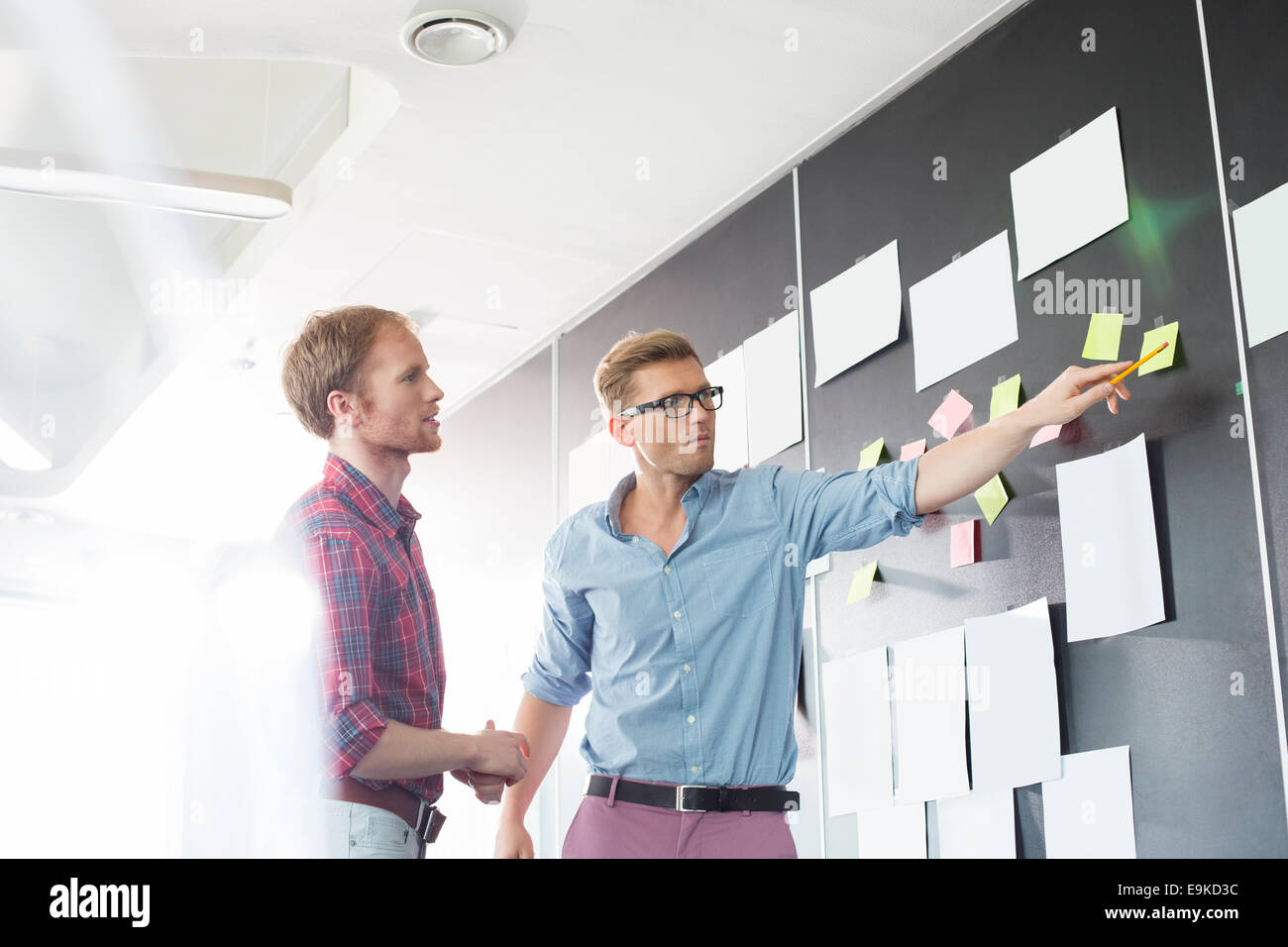 Kreative Unternehmer diskutieren über klebrige Papier an der Wand im Büro Stockfoto