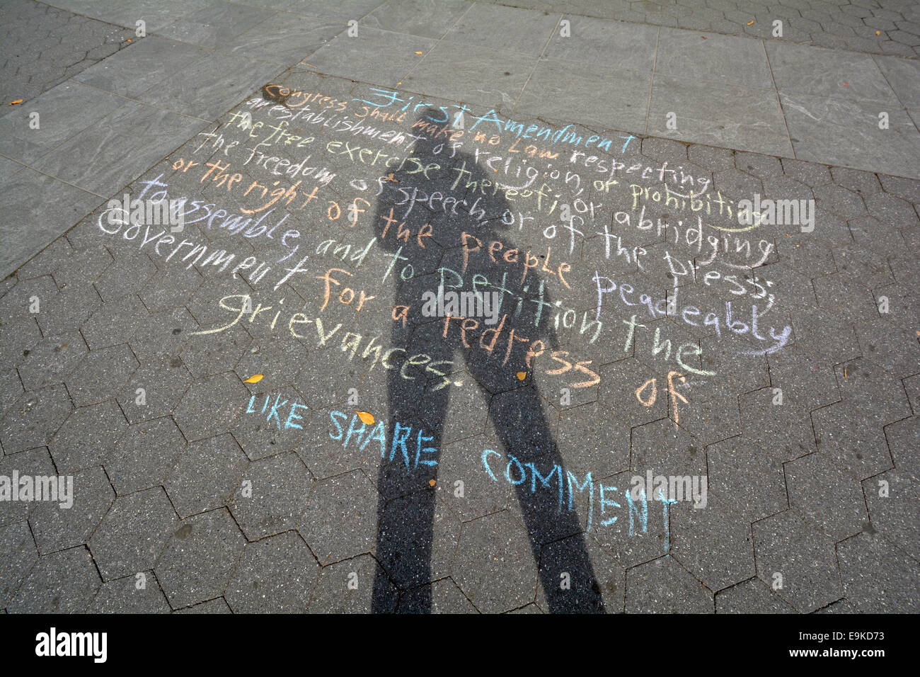 Ein Selbstportrait eines Fotografen, dessen Schatten erstreckt sich über eine Kreide Version des first Amendment. Im Washington Square Park. Stockfoto