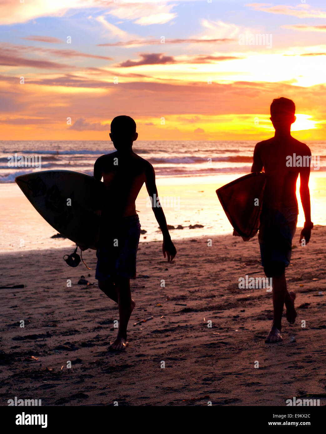 Zwei Surfer am Ocean Beach bei Sonnenuntergang auf der Insel Bali, Indonesien Stockfoto