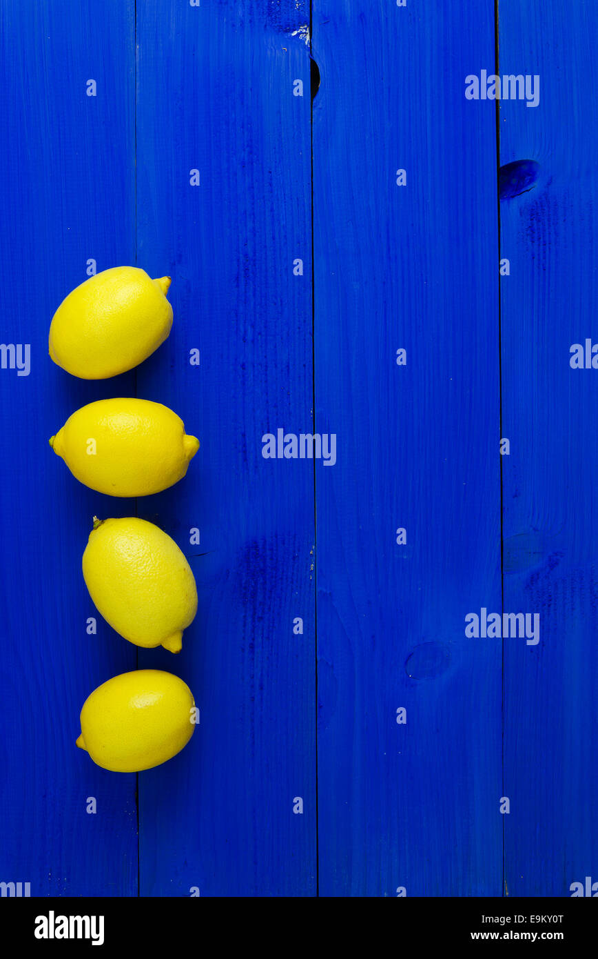 Vier Zitronen über blauen hölzernen Hintergrund mit textfreiraum (negativer Raum) Stockfoto