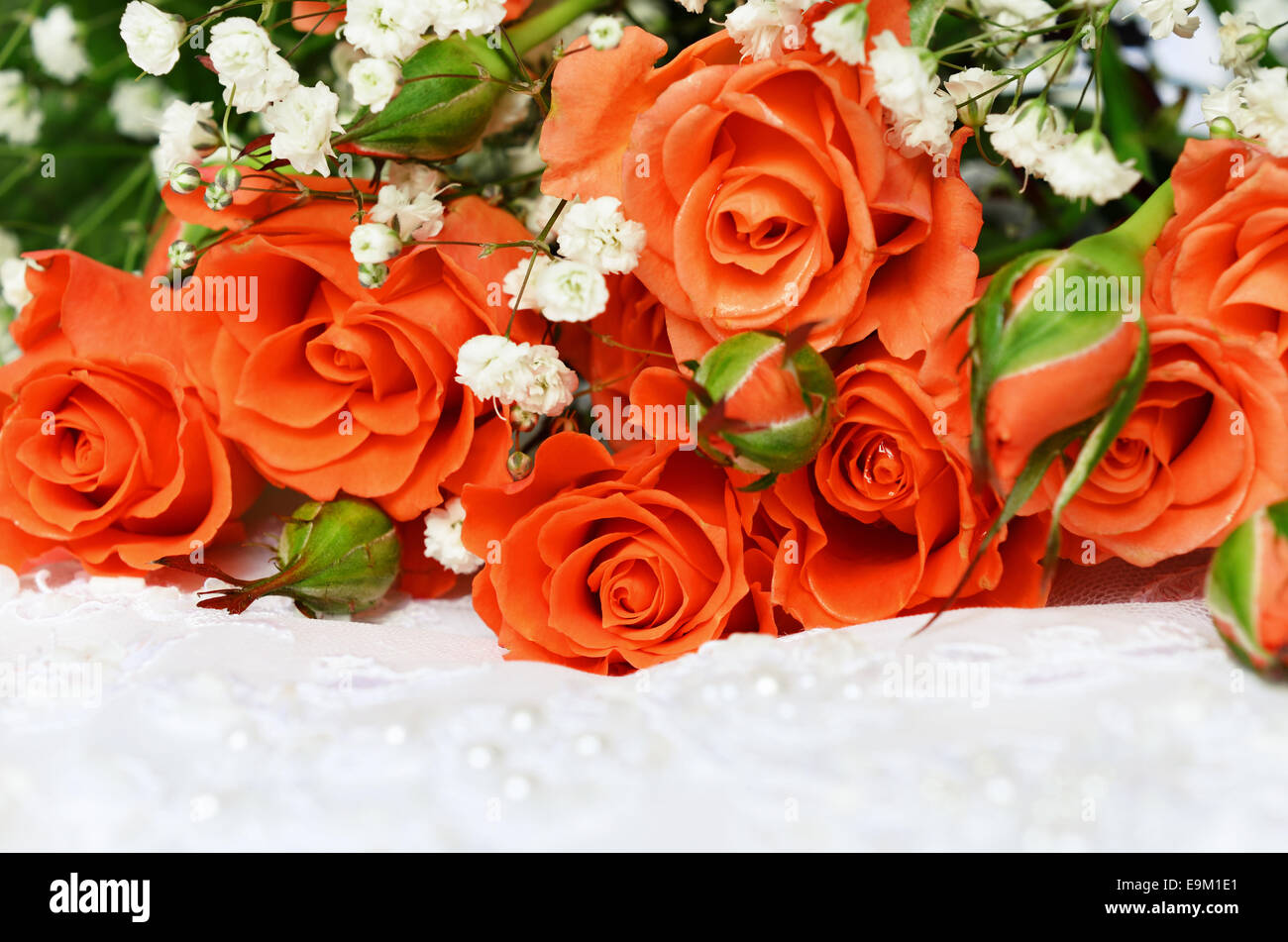 Orange Rosen auf weißes Hochzeitskleid Spitze Stockfoto