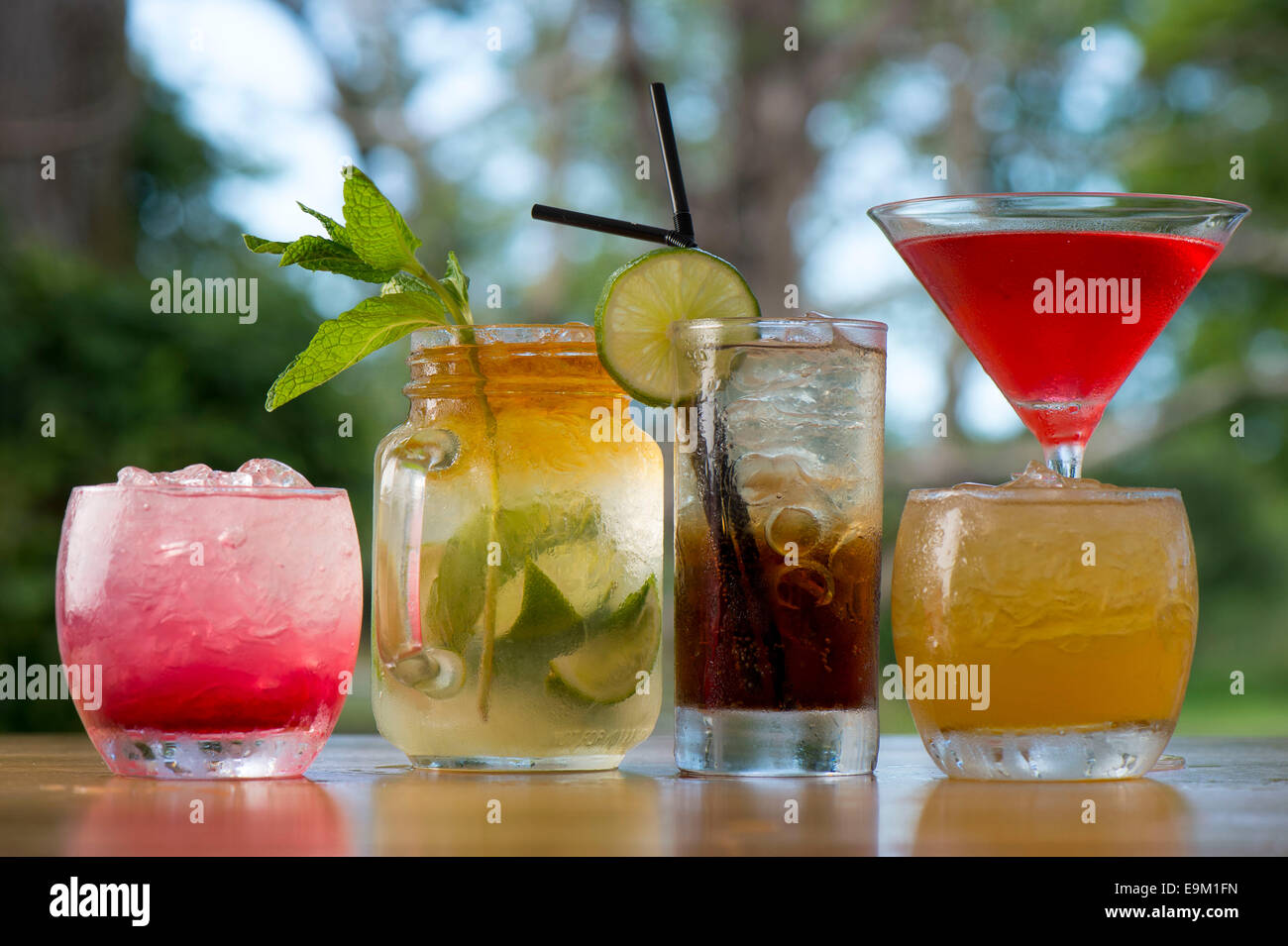 Eine Auswahl an Cocktails mit einem grünen aus Fokus Hintergrund. Stockfoto