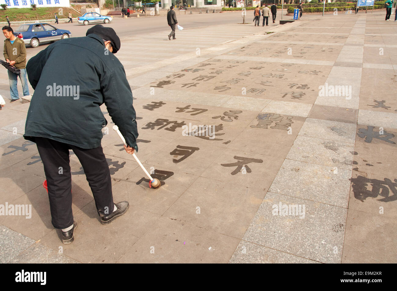 Ein Alter Mann schreiben verschwindenden chinesischen Schriftzeichen mit einem Schwamm, Luzhi, Provinz Guizhou, China Stockfoto