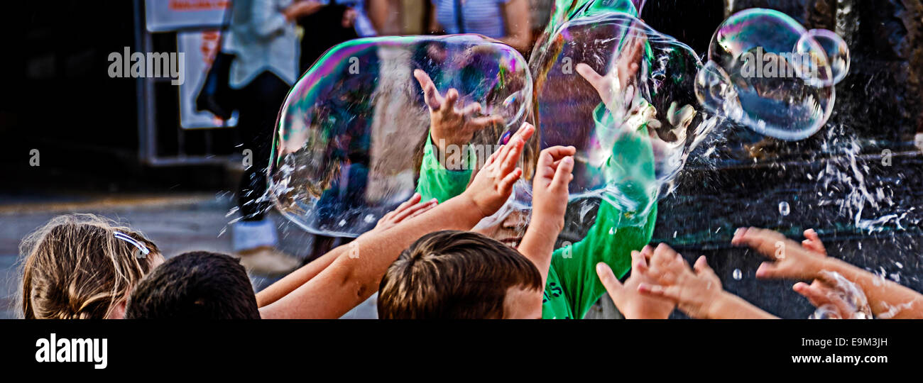 Kinder versuchen, einige Riesen-Seifenblasen zu fangen. Stockfoto