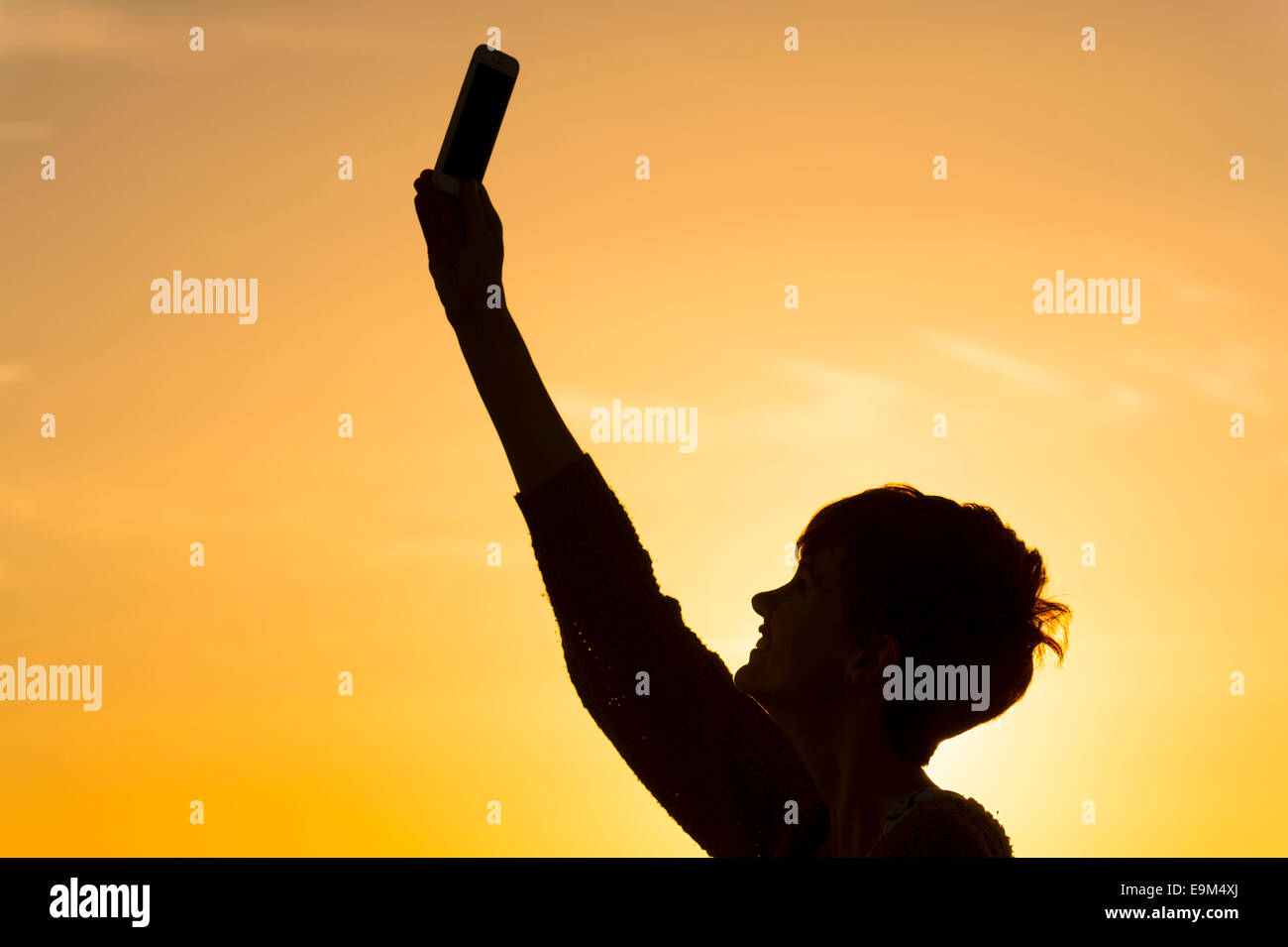 Eine Silhouette Mädchen hält ein Handy in die Luft zu versuchen und ein Datensignal erhalten. Stockfoto