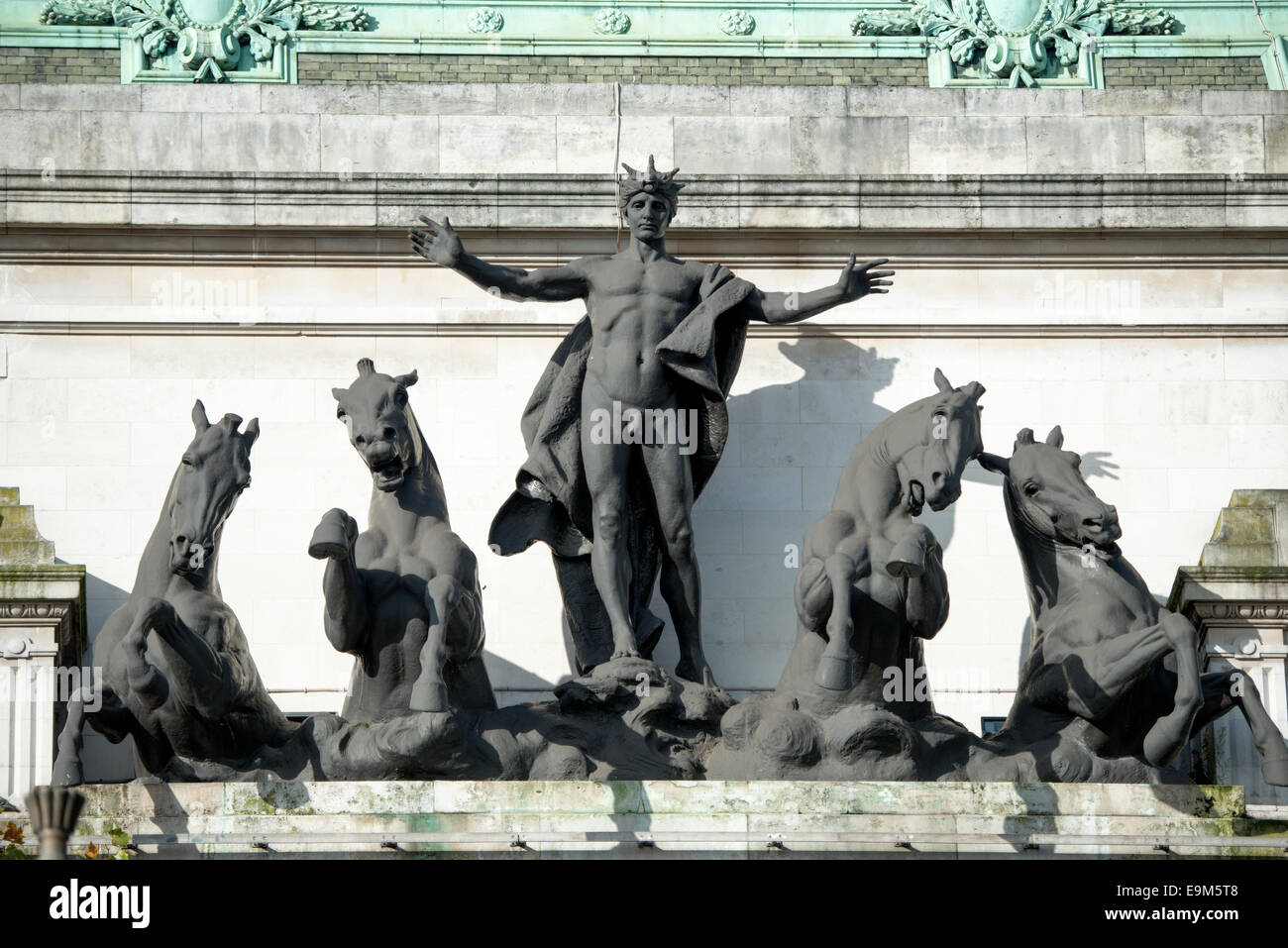 Australia House Quadriga Sculpture London // LONDON, Vereinigtes Königreich — die bronzene Quadriga-Skulptur krönt die zentrale Fassade des Australia House on the Strand und zeigt einen Jugendlichen Wagenkämpfer, der vier Pferde führt, die einen zeremoniellen Wagen ziehen. Die Skulpturengruppe wurde 1918 fertiggestellt und dient als prominentes architektonisches Merkmal des diplomatischen Hauptquartiers Australiens in London. Die Quadriga, ein klassisches Motiv, das einen Vierpferdewagen darstellt, symbolisiert Australiens aufkommenden nationalen Status im britischen Empire während des frühen 20. Jahrhunderts. Australia House selbst war des Stockfoto