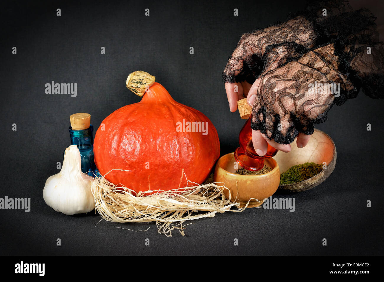 Hände der Hexe in schwarzen Handschuhen, die Kräutermischung für Halloween feiern vorbereiten Stockfoto