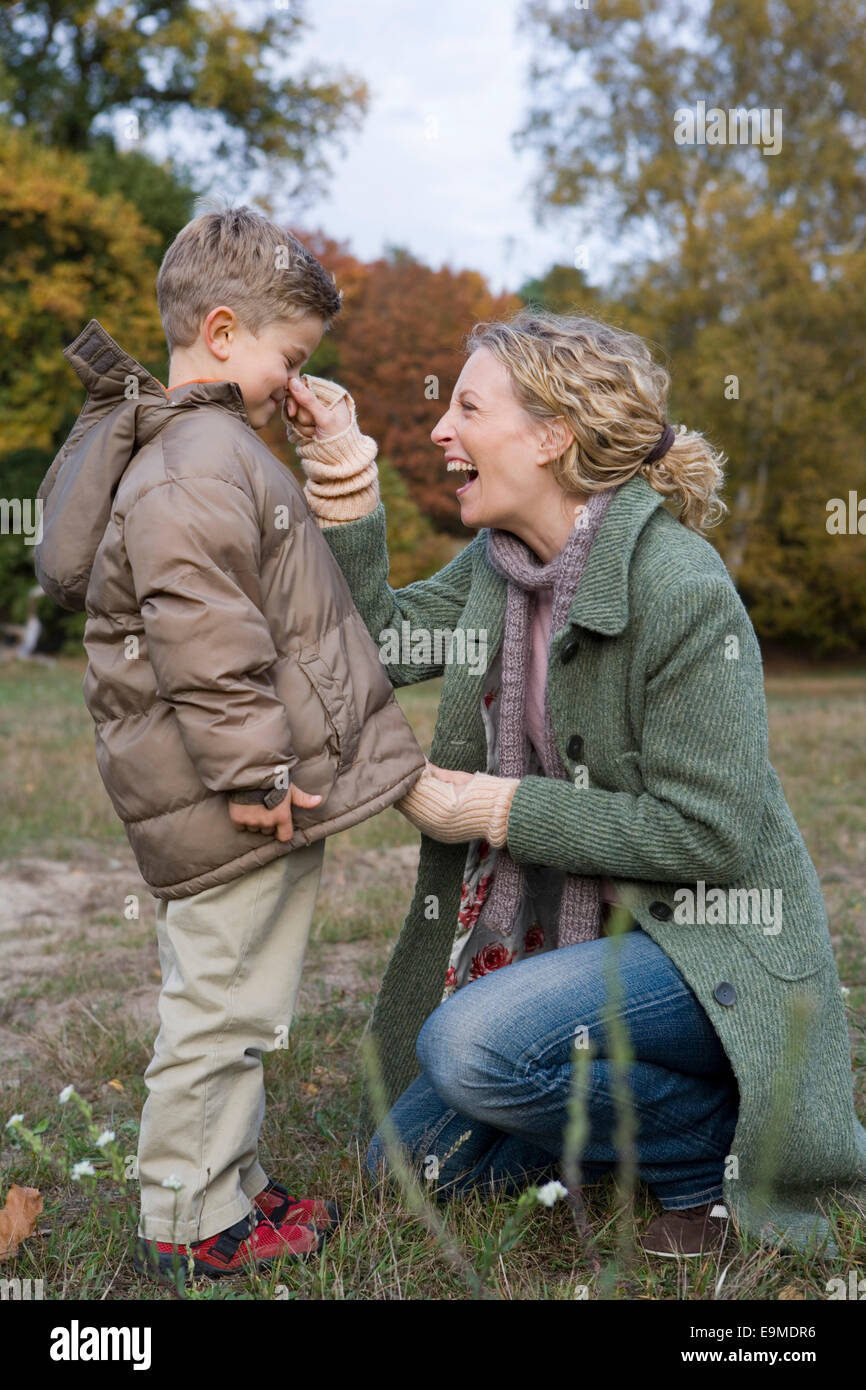 Mutter Sohn die Nase im Park kneifen während Reißverschluss oben Parka Stockfoto