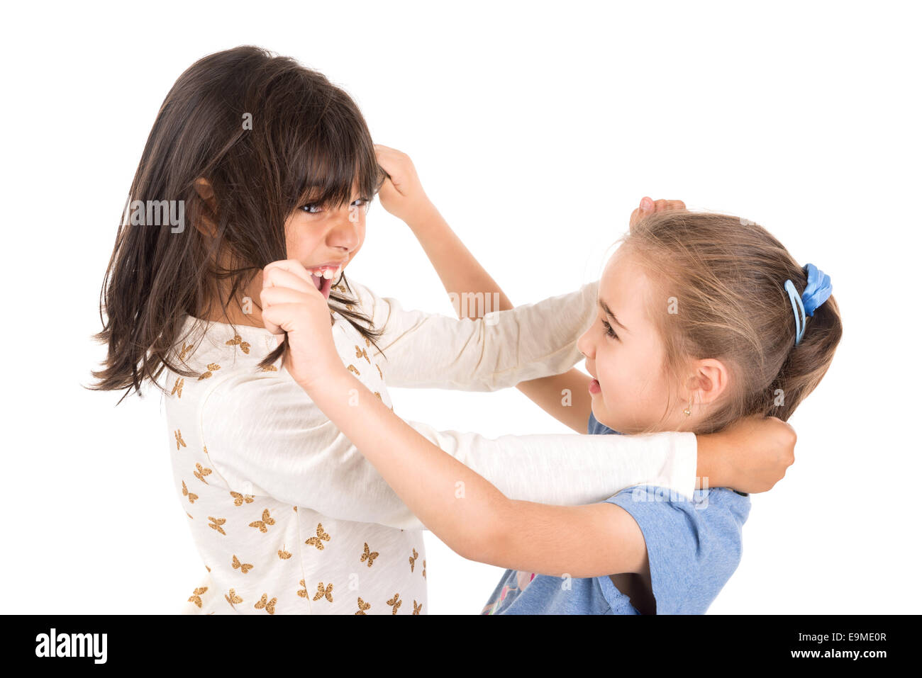 Junge Mädchen kämpfen, ziehen Haare isoliert in weiß Stockfoto