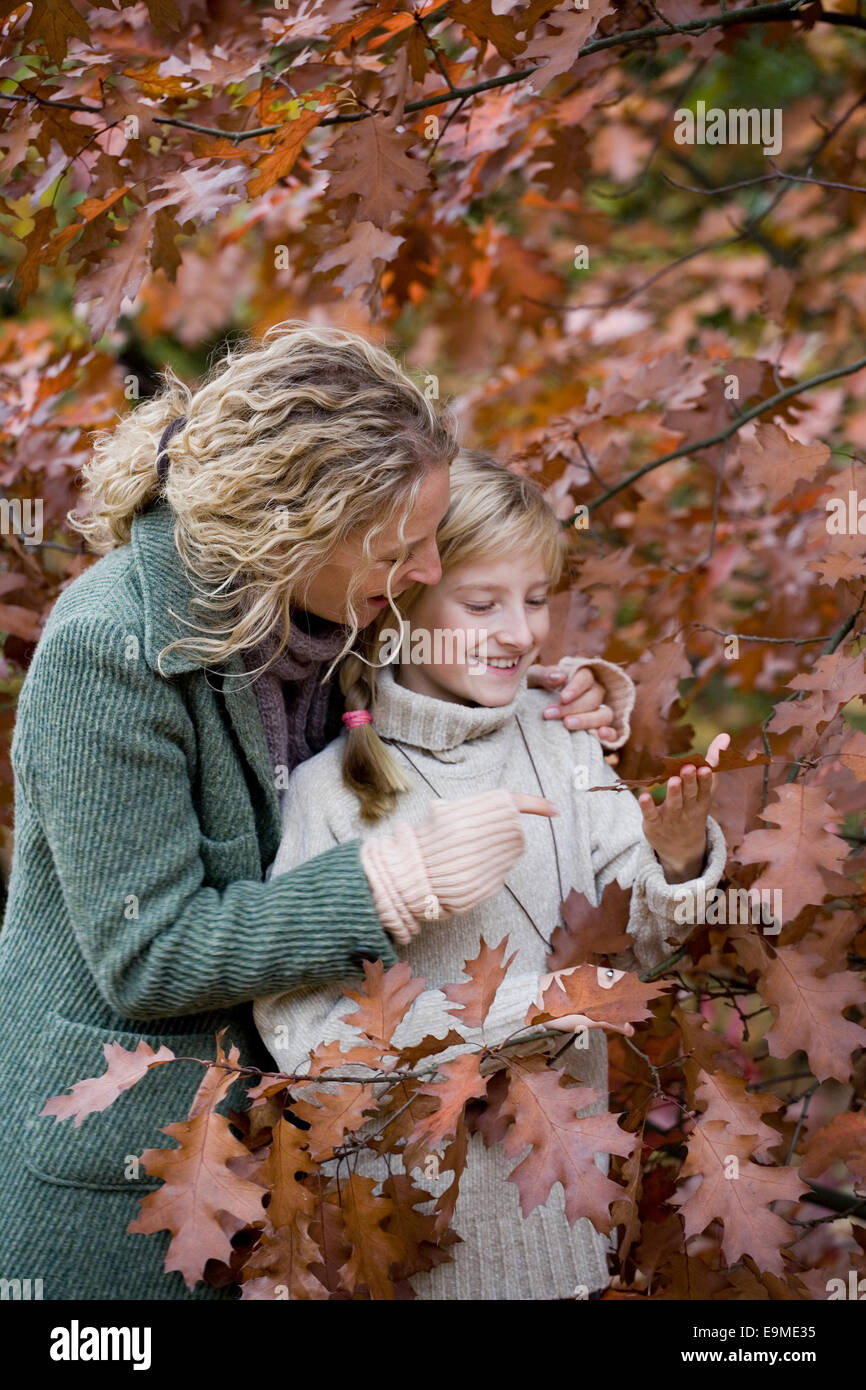 Mutter und Tochter stehen unter Ästen mit Herbstlaub Stockfoto