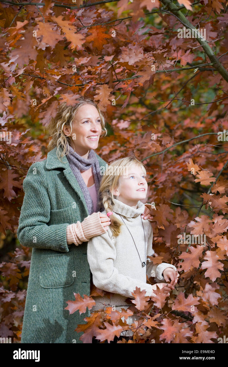 Mutter und Tochter stehen unten Äste im Wald Stockfoto