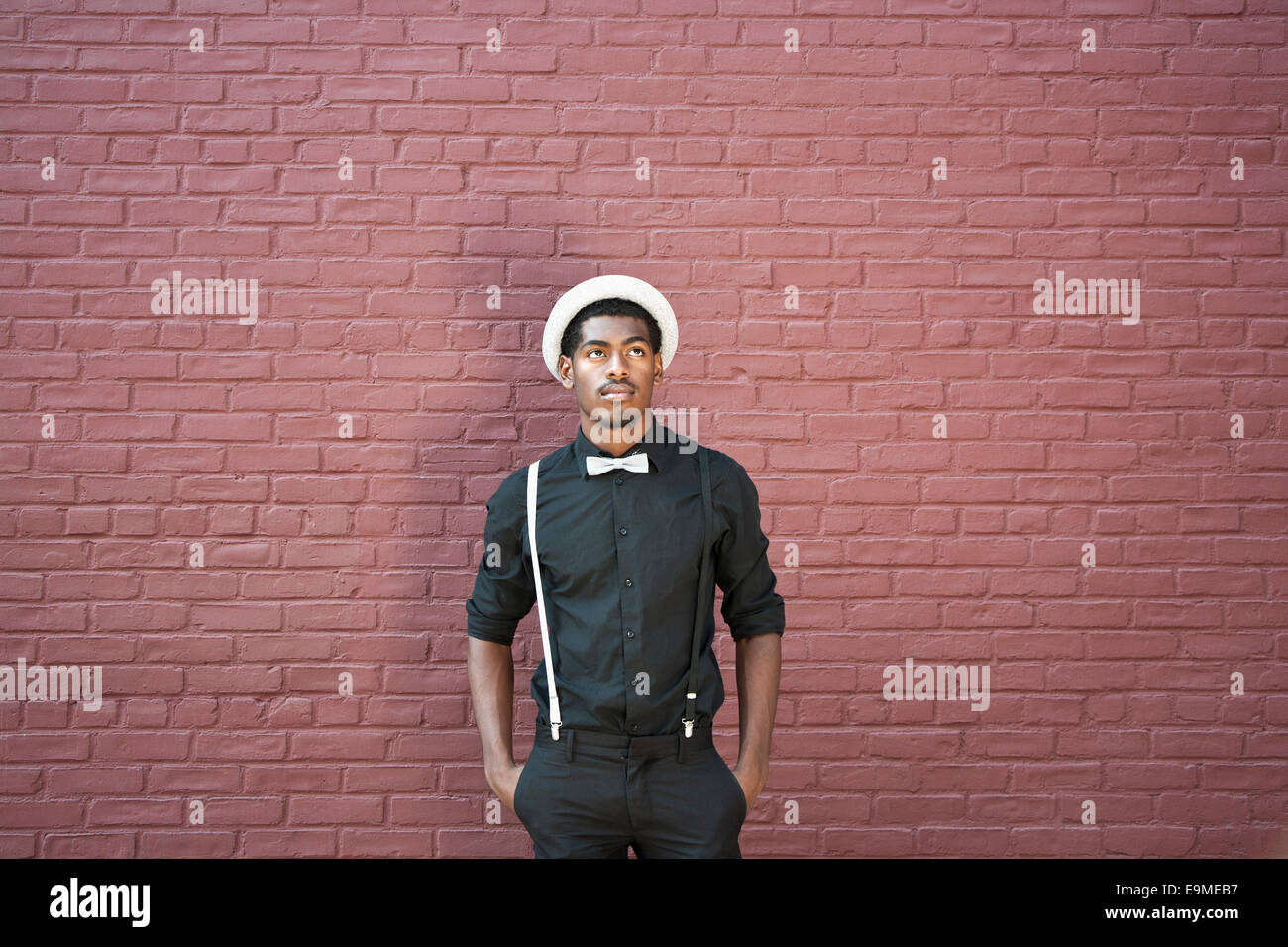 Ein junger schwarzer Mann gekleidet in Fliege, Hosenträger und Hut Stockfoto