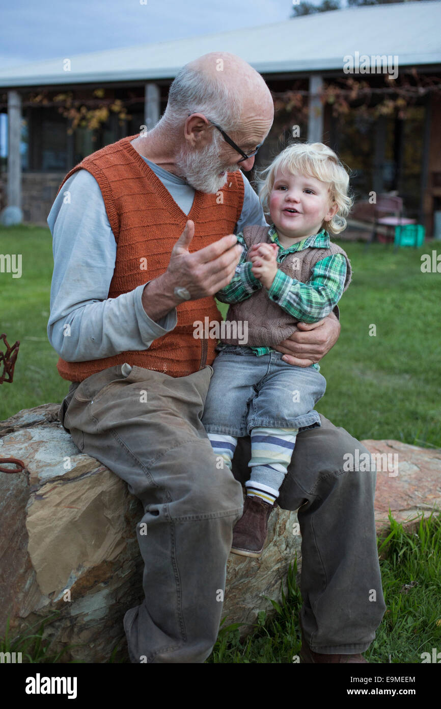 Süße junge sitzt auf Großvaters Schoß im park Stockfoto