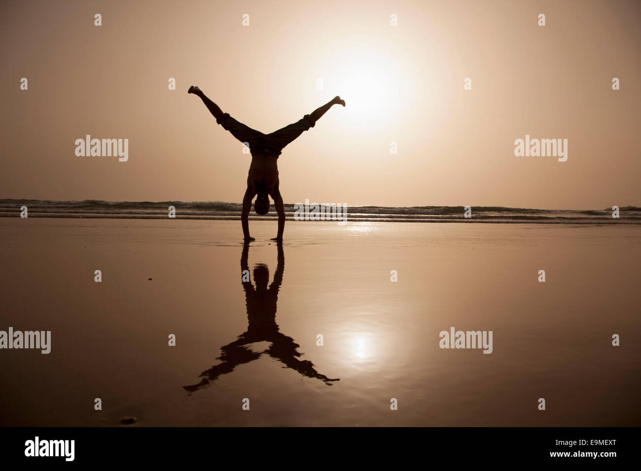 Gesamte Länge der Silhouette Mann Durchführung Handstand am Strand Stockfoto