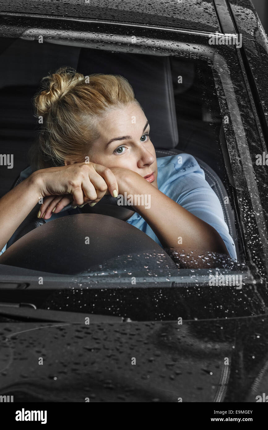 Gelangweilte Frau wegsehen und stützte sich auf Lenkrad im Auto Stockfoto