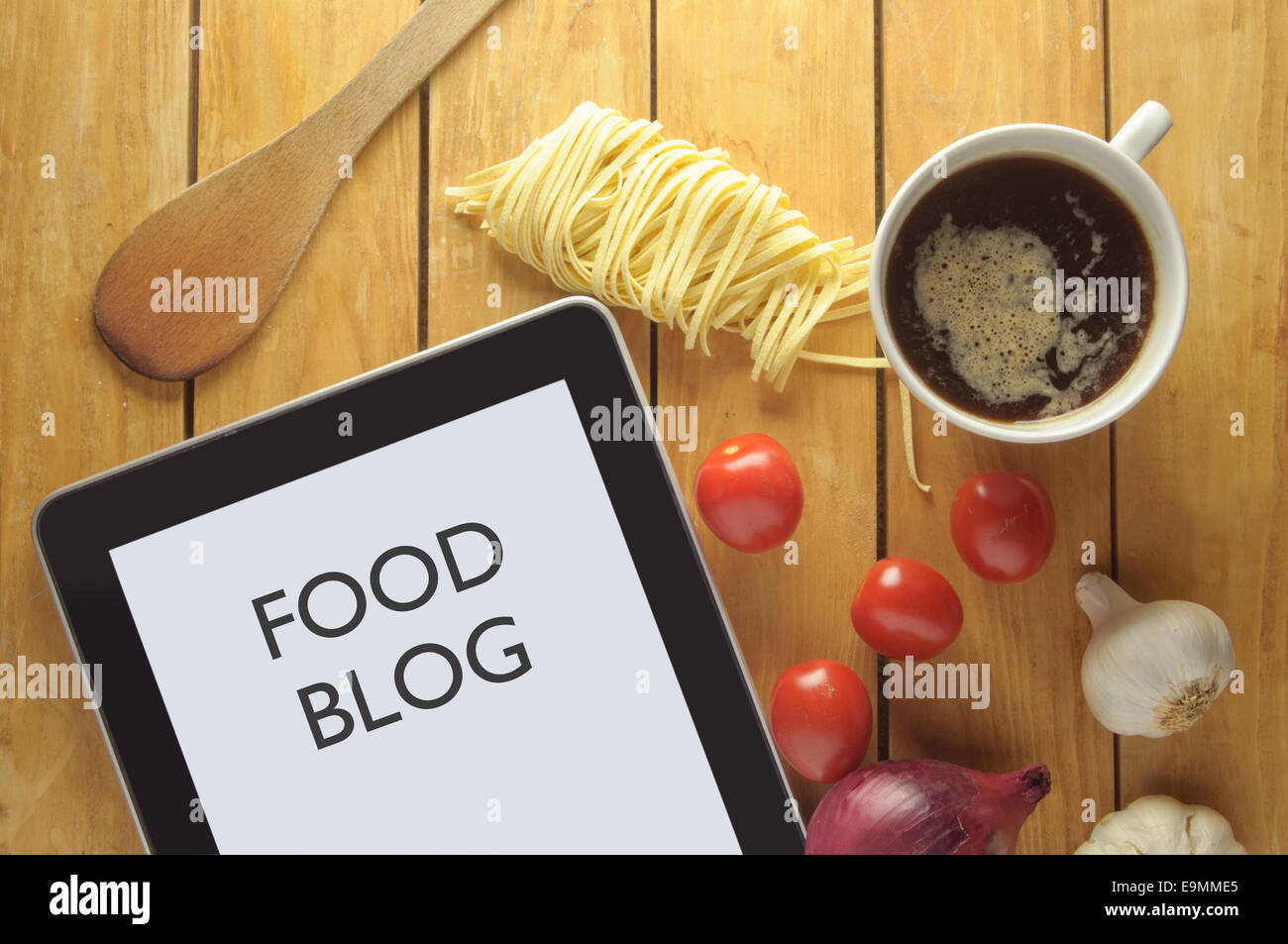 Essen-Blog-Überschrift auf einem Tablet, umgeben von frischen Zutaten Stockfoto