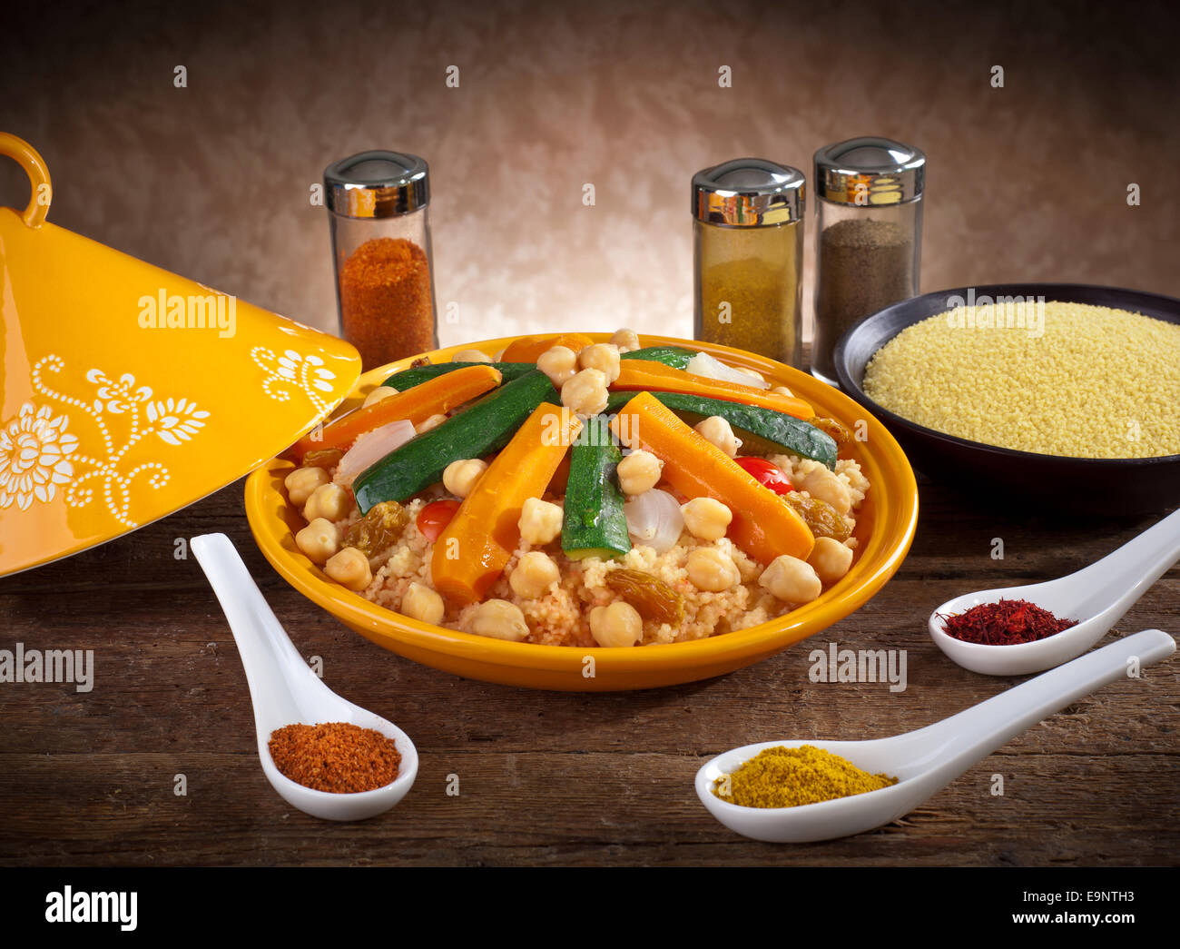 Gemüse-Tajine mit Couscous und Gewürzen auf Holztisch. Stockfoto