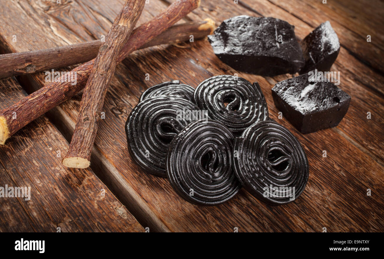 Produktionsschritte von Lakritz, Wurzeln, reine Blöcke und Süßigkeiten auf Holztisch Stockfoto