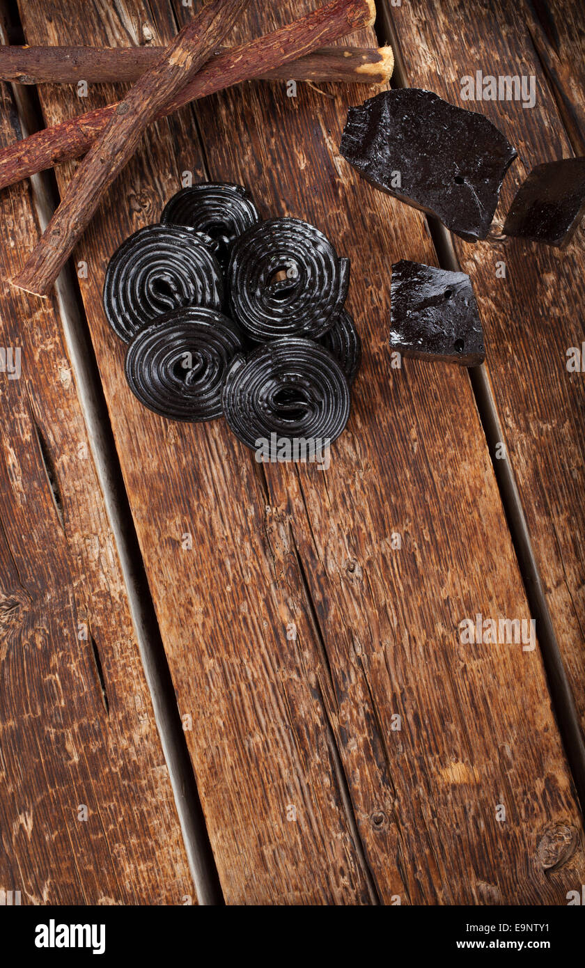 Produktionsschritte von Lakritz, Wurzeln, reine Blöcke und Süßigkeiten auf Holztisch Stockfoto