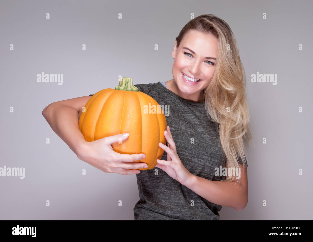 Porträt der hübsche lächelnde Frau mit frischen Reifen Kürbis in Händen isoliert auf grauem Hintergrund, Thanksgiving Day Feier Stockfoto