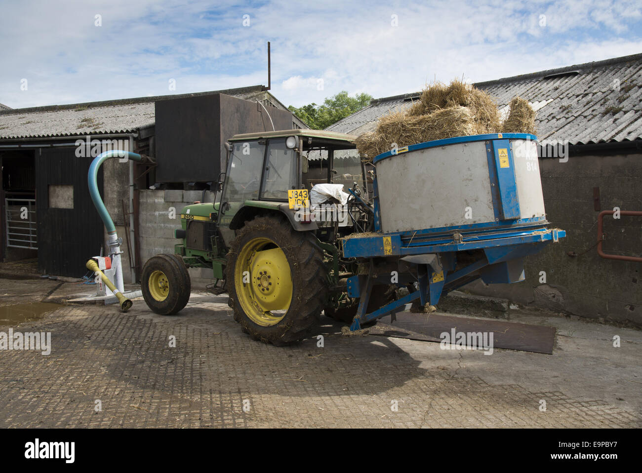 John Deere 2450 Traktor mit Stroh Einstreu Maschine auf Milchviehbetrieb, Preston, Lancashire, England, Juli Stockfoto